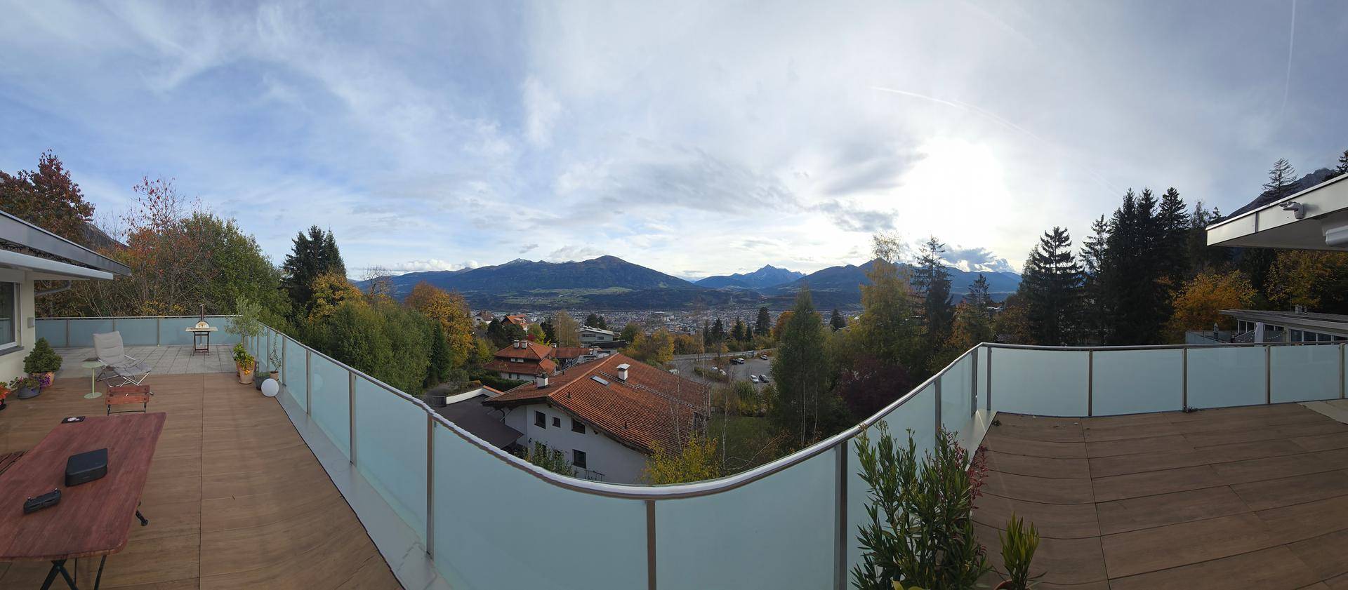 Weitläufige Terrasse mit Holzboden und Glasgeländer, bietet einen Panoramablick auf die Umgebung.