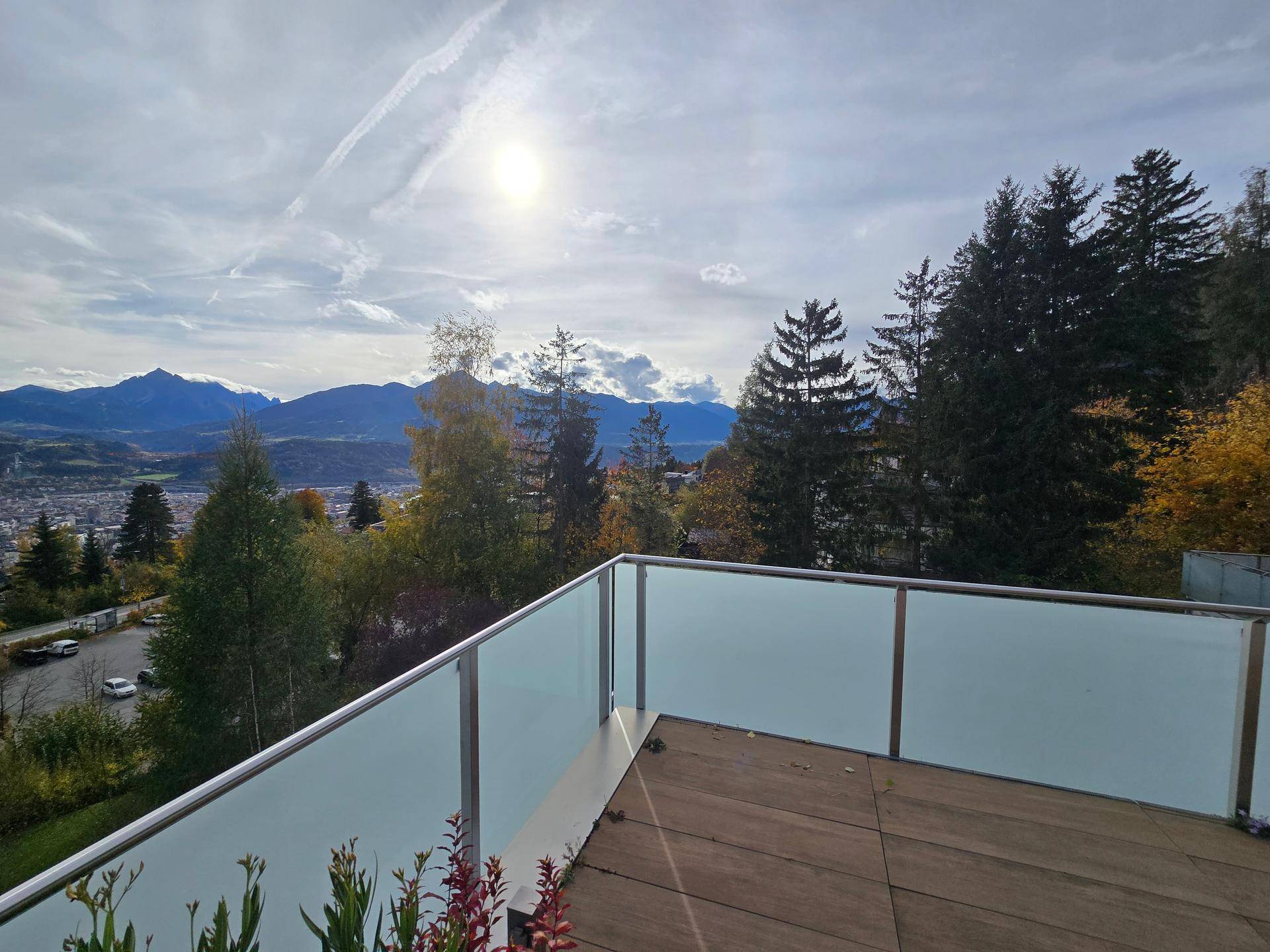 Sonniger Terrassenbereich mit Glasgeländer und weitem Blick auf die Berge und die Umgebung.