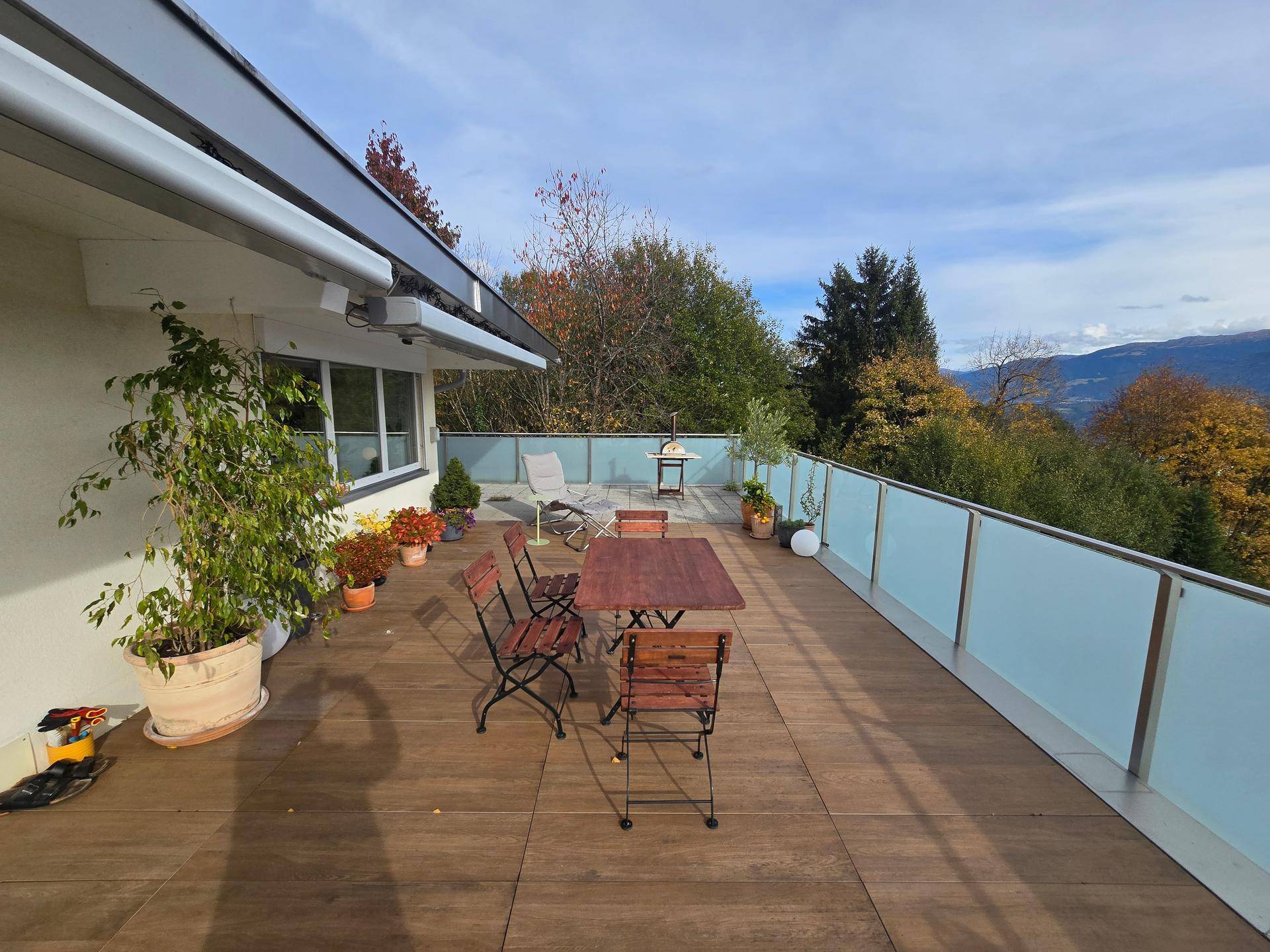 Große Sonnenterrasse mit Holzboden, Gartenmöbeln und weitem Blick auf die Landschaft.