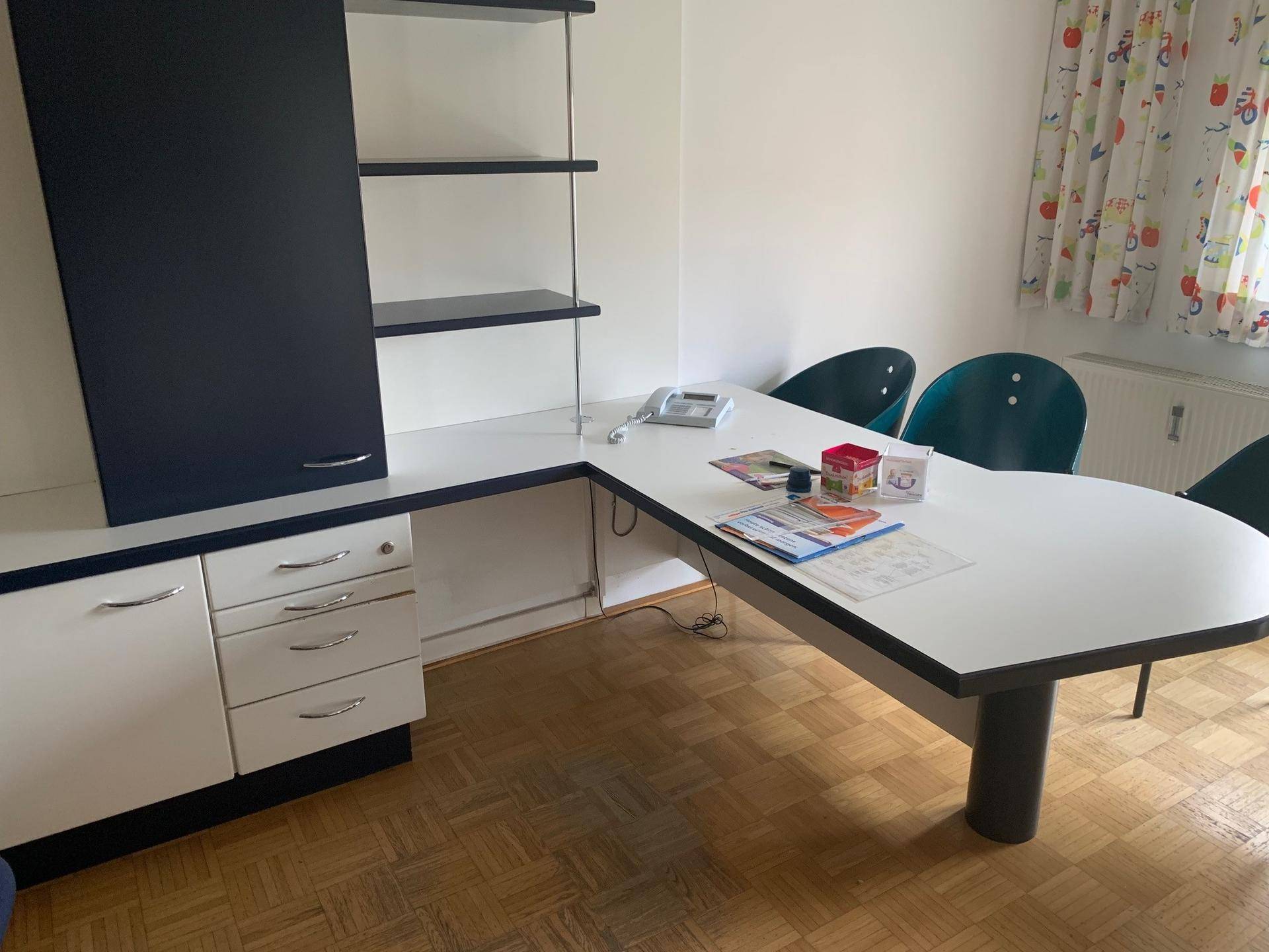 Geräumiges Büro mit großem Schreibtisch, Regalen und viel natürlichem Licht durch das Fenster.
