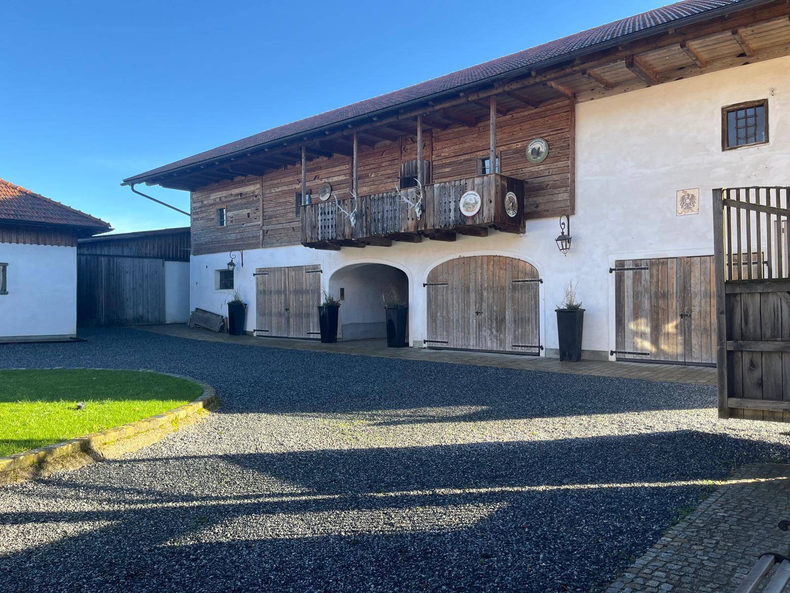 Historisches Hofgebäude mit großen Holztoren, Balkon und traditionellen Hirschgeweih-Verzierungen.