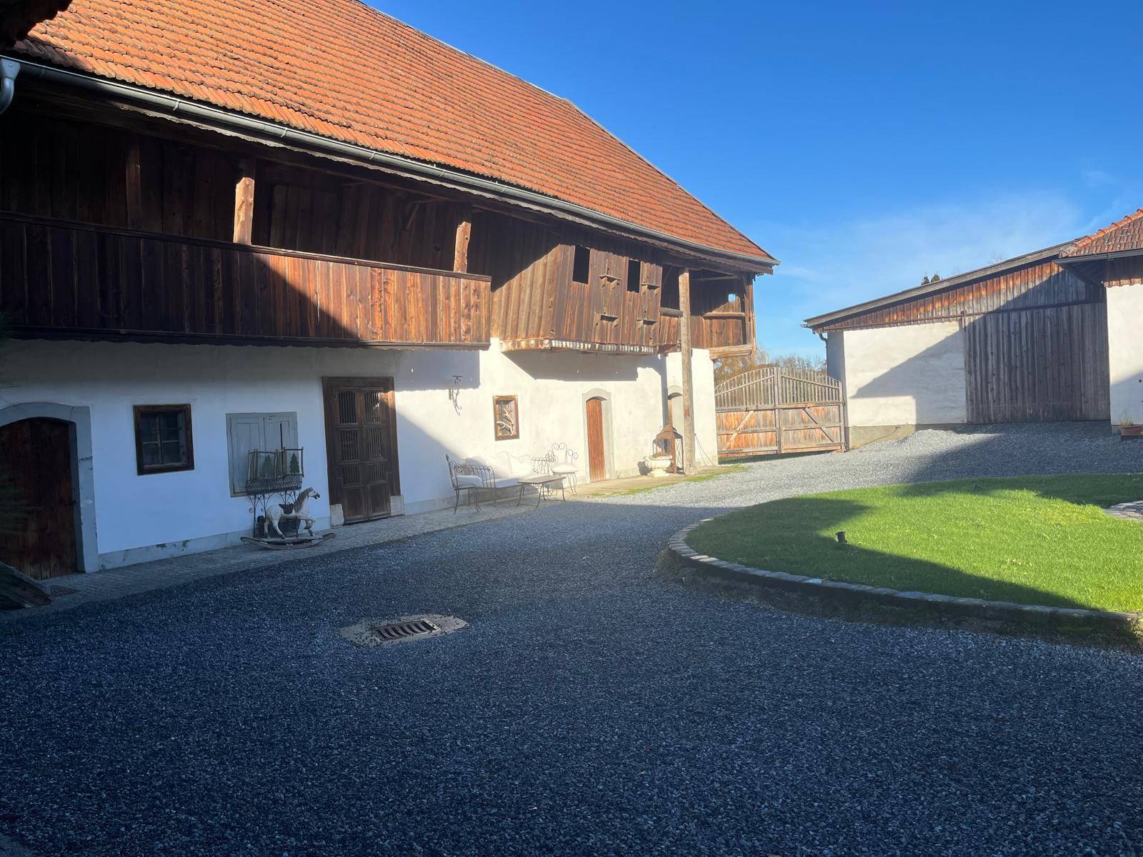 Traditionelle Hofanlage mit Holzbalkonen, Kiesfläche und Blick auf die umliegende Landschaft.