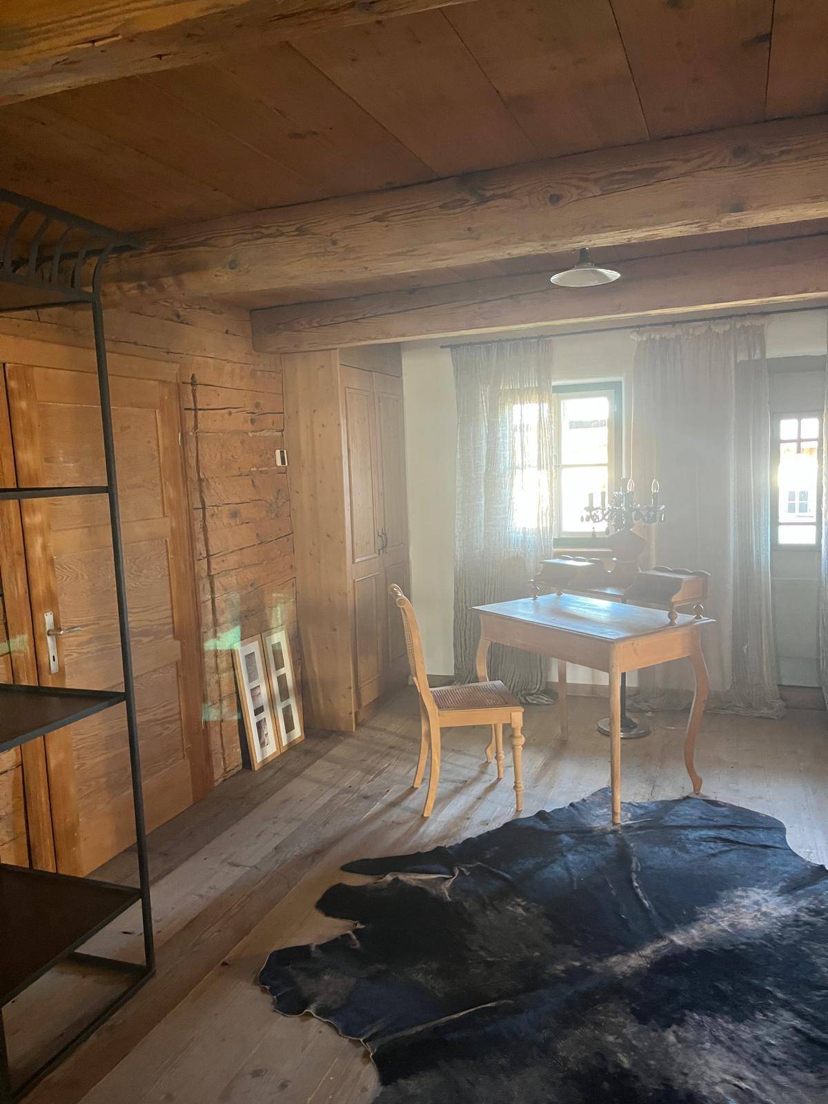 Helles Arbeitszimmer mit Holzboden, Holzwänden und einem klassischen Schreibtisch am Fenster.