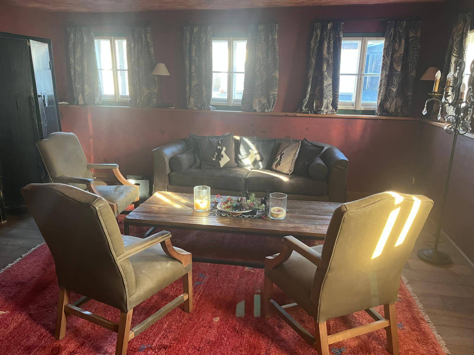 Helles Wohnzimmer mit rotem Teppich, bequemen Sofas und traditioneller, einladender Einrichtung.