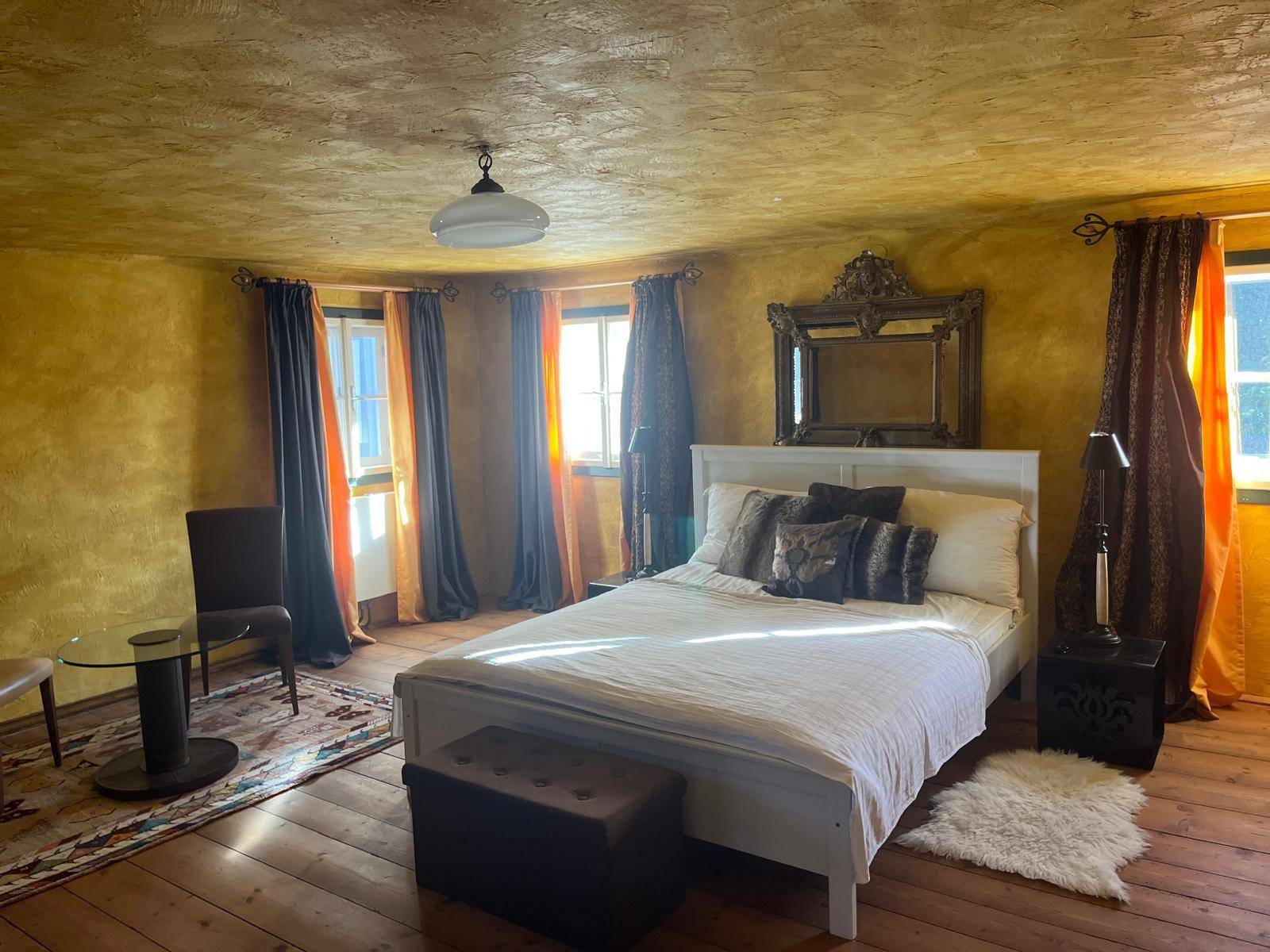 Gemütliches Schlafzimmer mit Holzboden, goldfarbenen Wänden und traditioneller, heller Einrichtung.