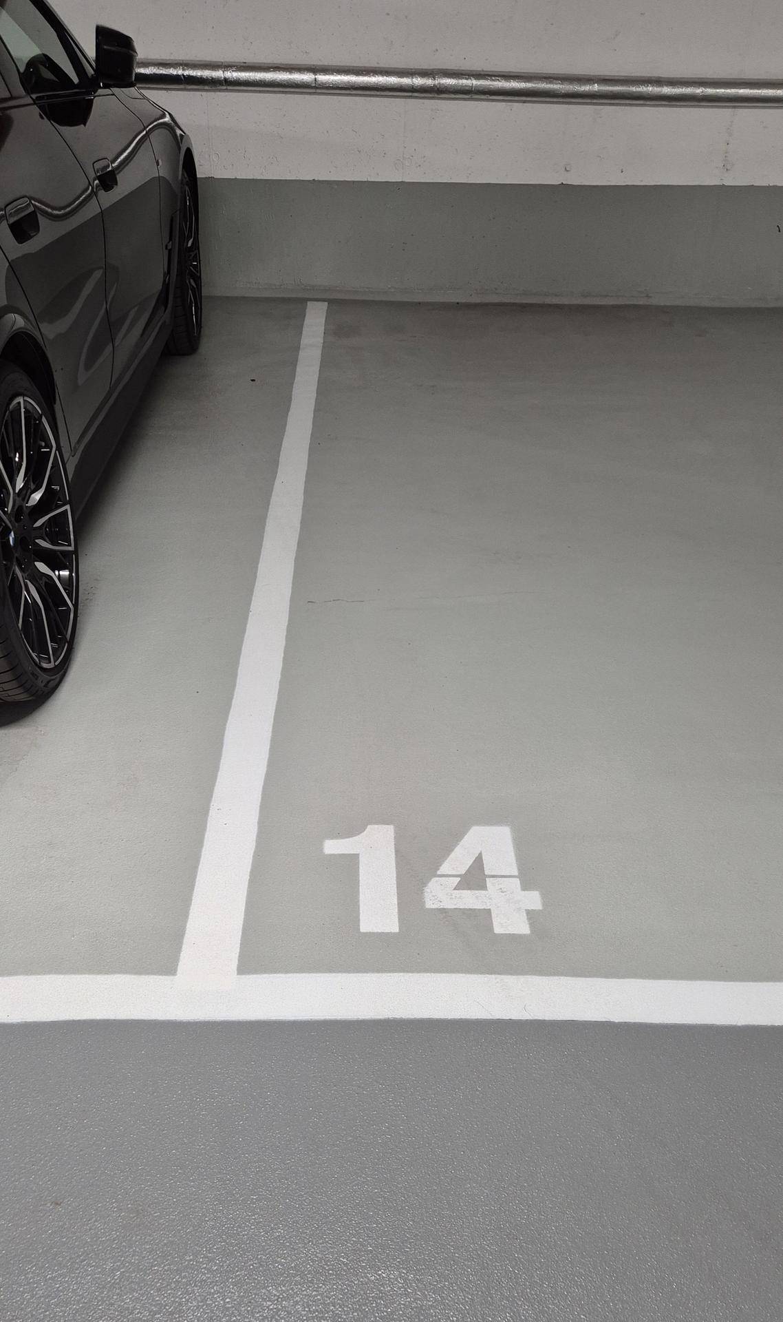 Nahaufnahme eines markierten Stellplatzes Nummer 14 in der Tiefgarage mit einem Fahrzeug.