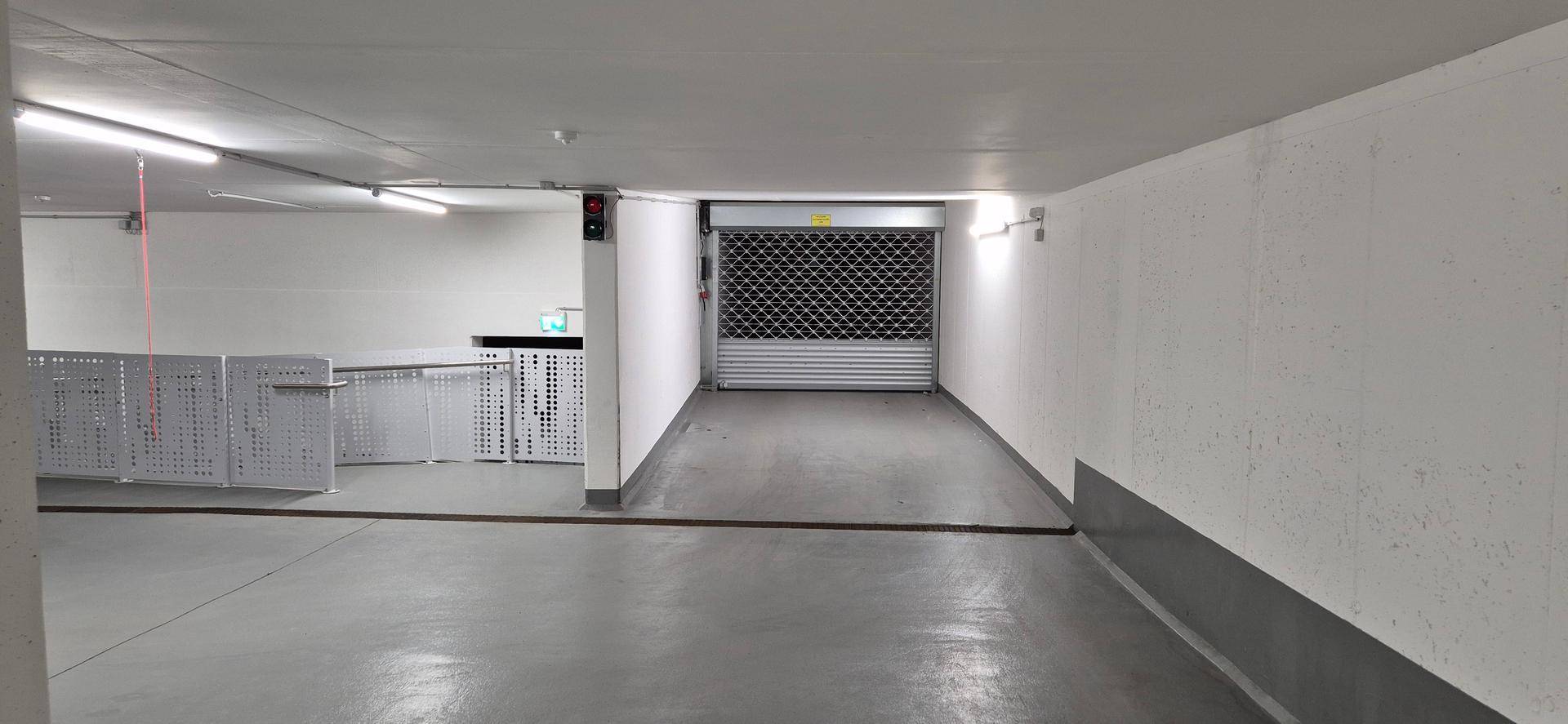 Einfahrt zur Tiefgarage mit geschlossenem Rolltor und einem Bereich für Fahrradabstellplätze.