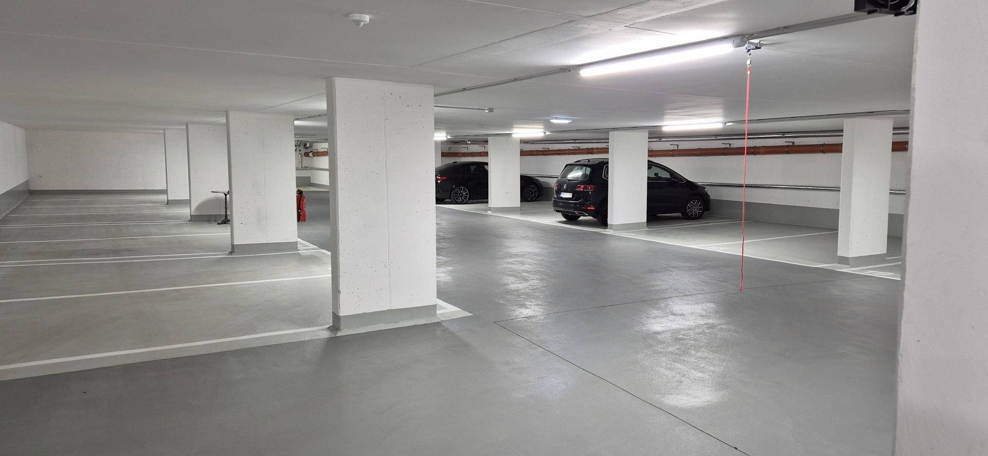 Tiefgarage mit mehreren geparkten Fahrzeugen und gut beleuchteten, breiten Fahrgassen.