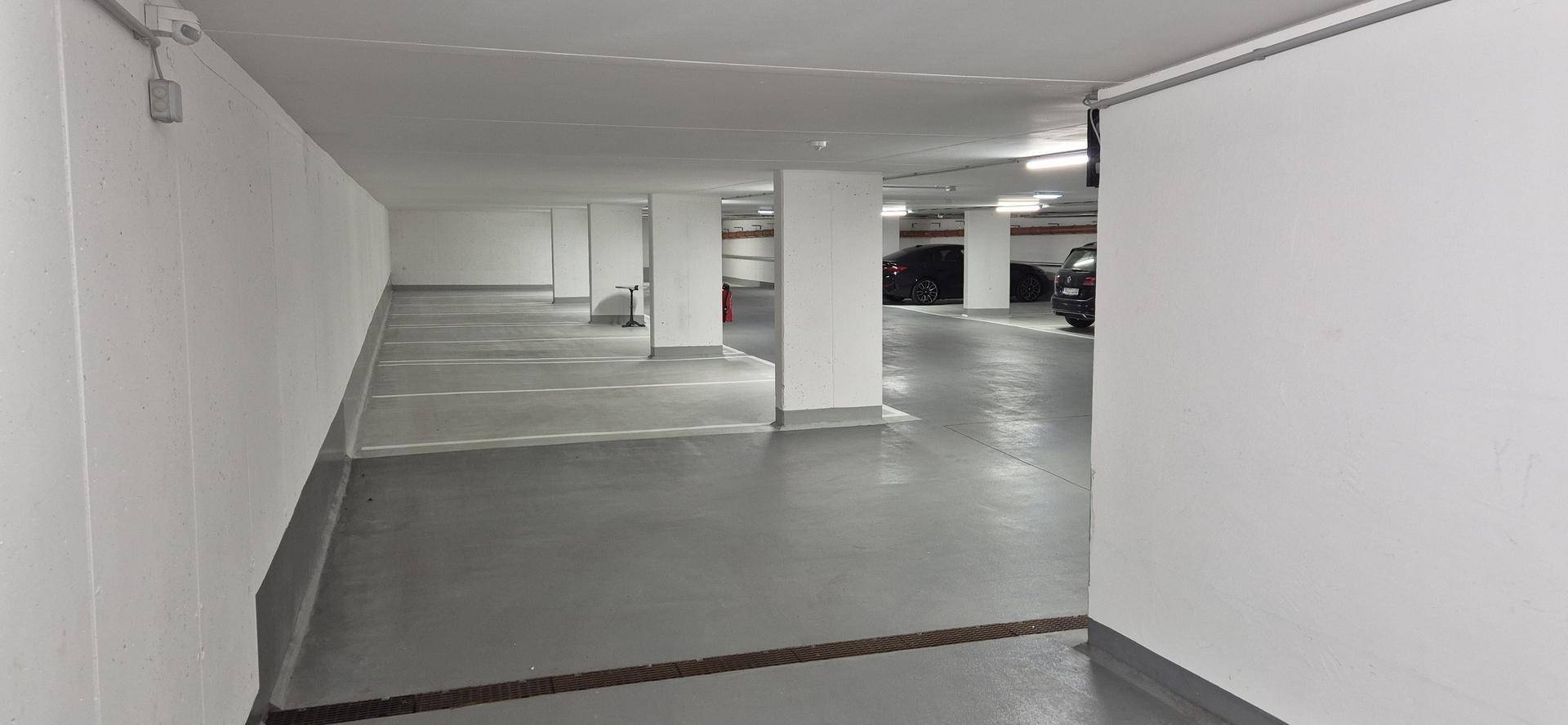 Langer Gang in einer Tiefgarage mit leeren Stellplätzen und sauberem Betonboden.