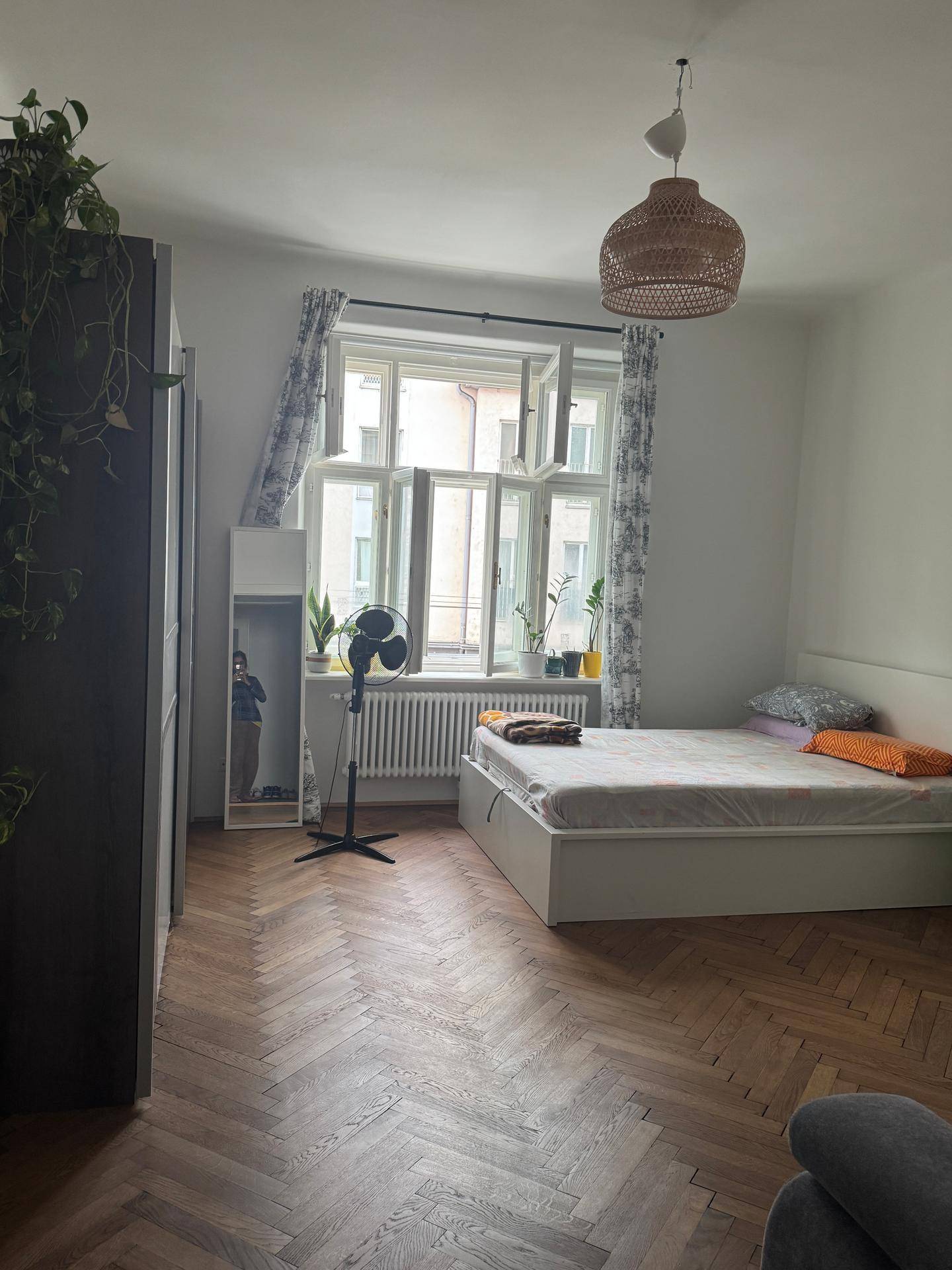 Helles Schlafzimmer mit Doppelbett, Fischgrätparkett und großem Fenster mit Blick auf den Innenhof.