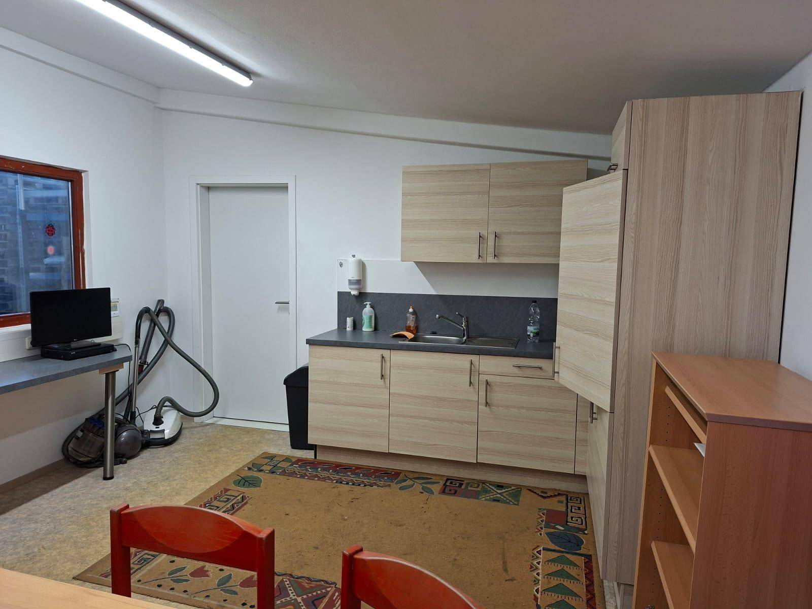 Kleine Küche mit Fenster, Holzschränken und einem Essbereich, ausgestattet für den täglichen Gebrauch.