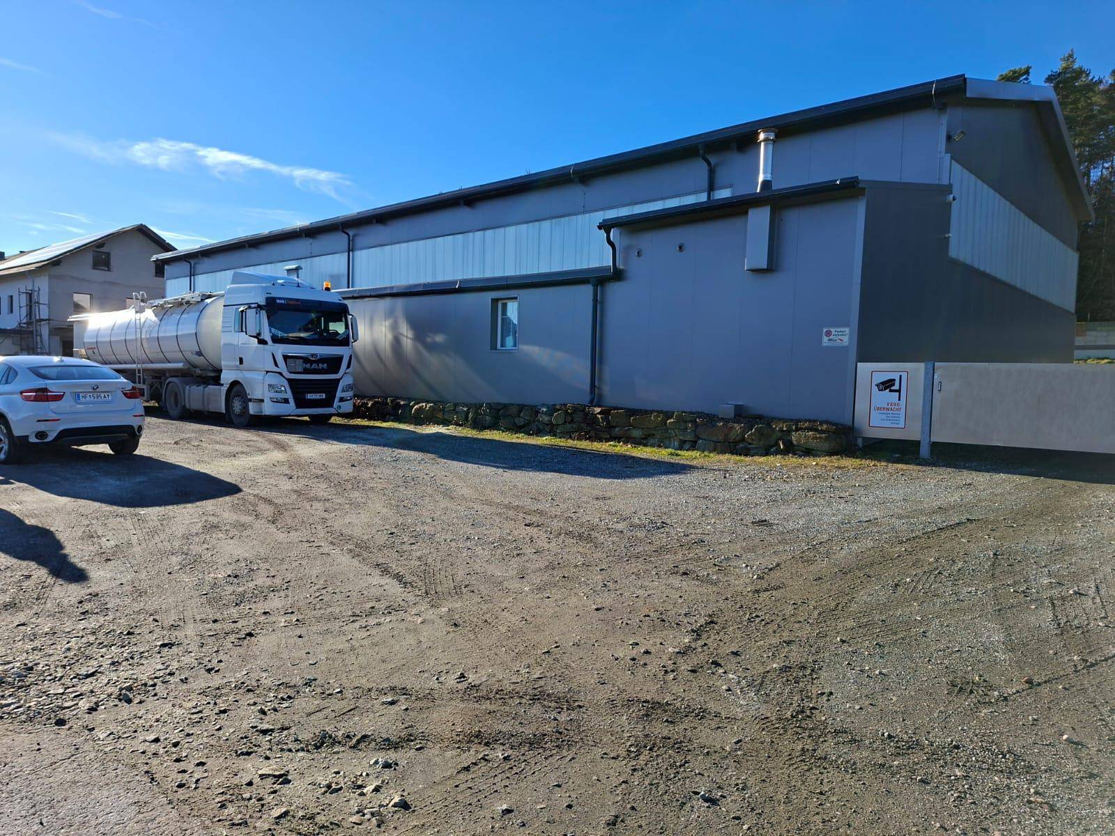 Seitenansicht des Gewerbegebäudes mit parkendem LKW und sichtbarer Überwachungskamera am Eingangsbereich.