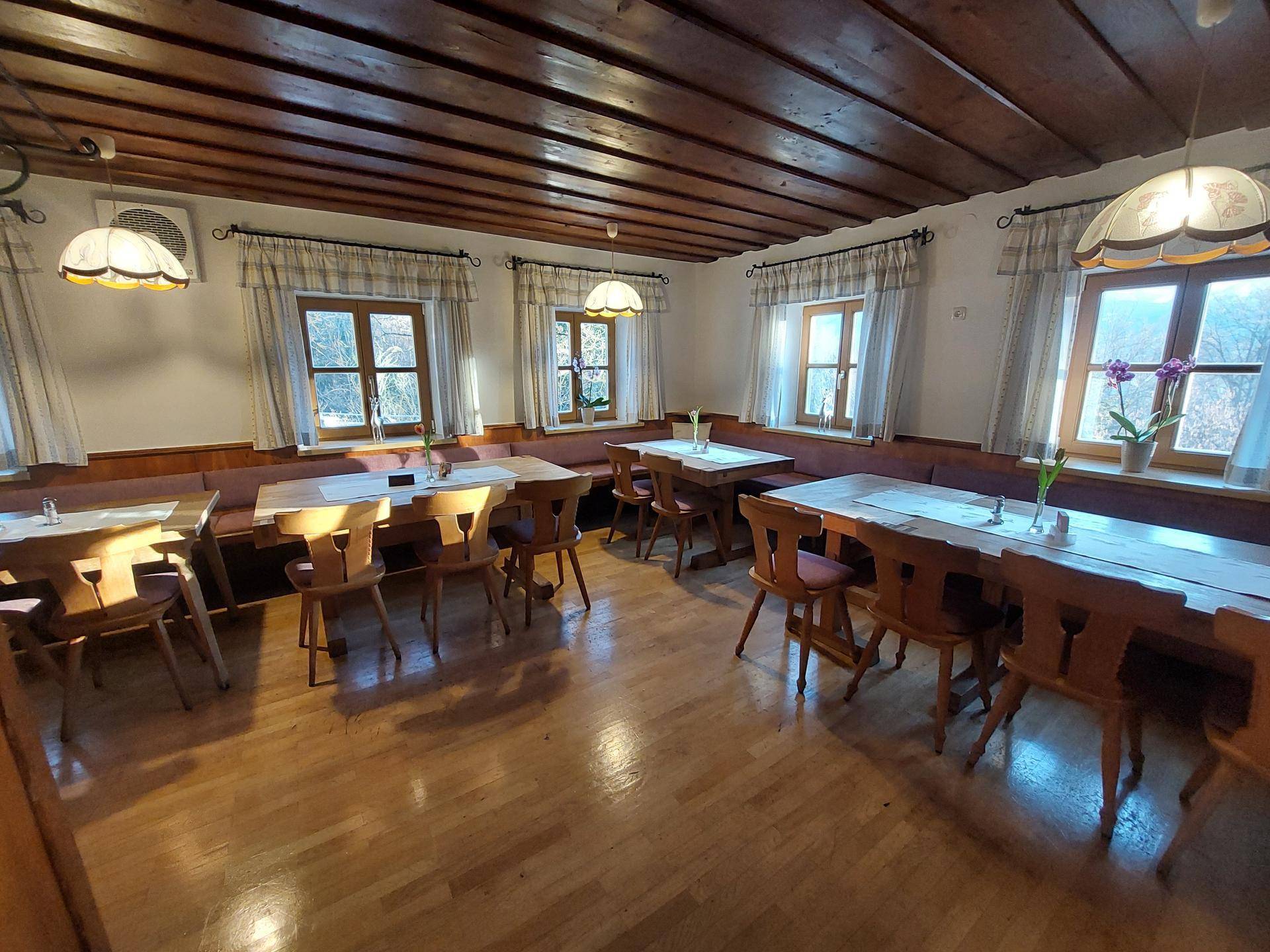 Gemütlicher Speisesaal mit Holzbalkendecke, Holzböden und traditionellen Sitzgelegenheiten an den Fenstern.