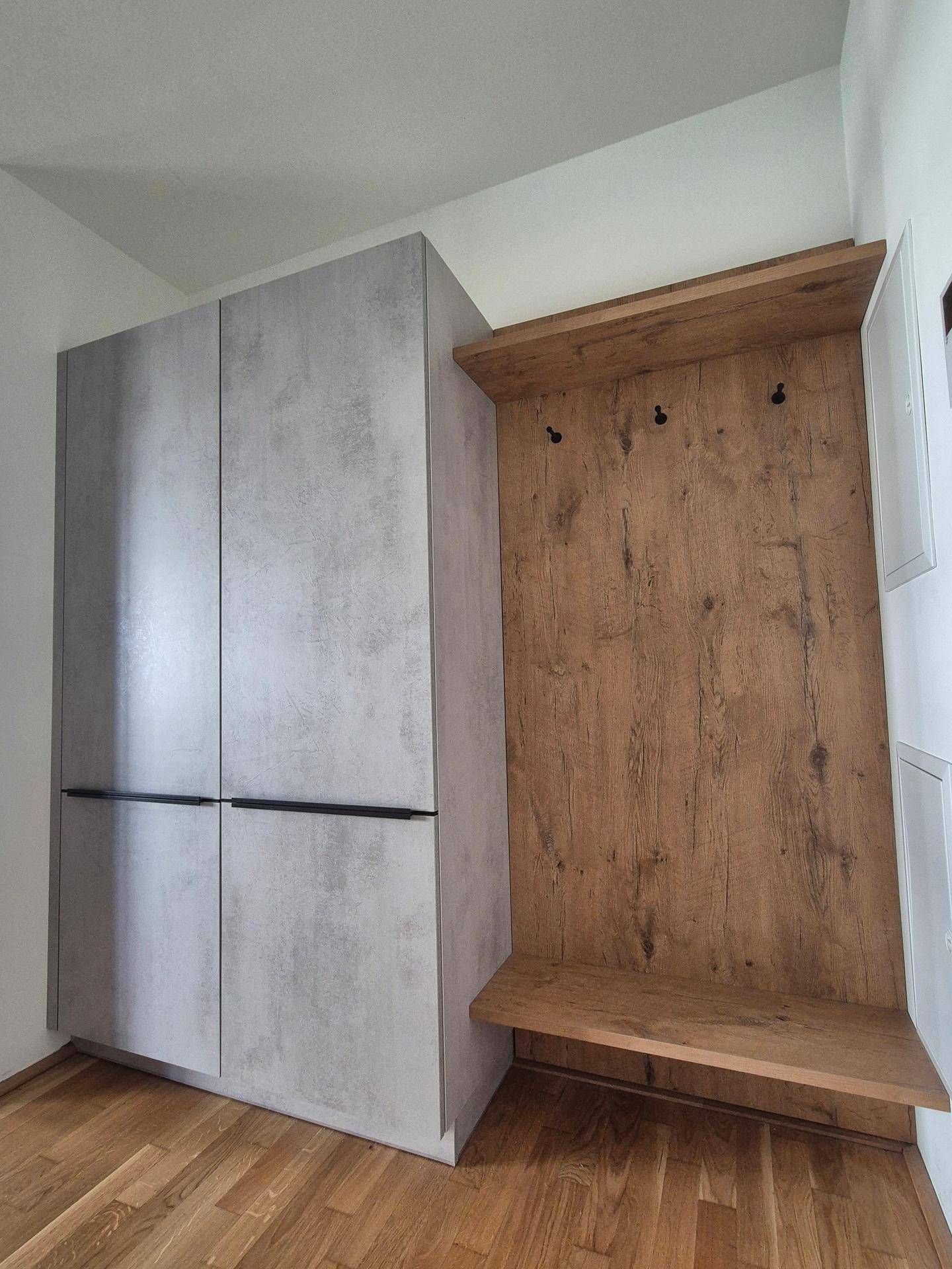 Moderner Eingangsbereich mit integrierten Schränken und Garderobe in Holz- und Betonoptik.