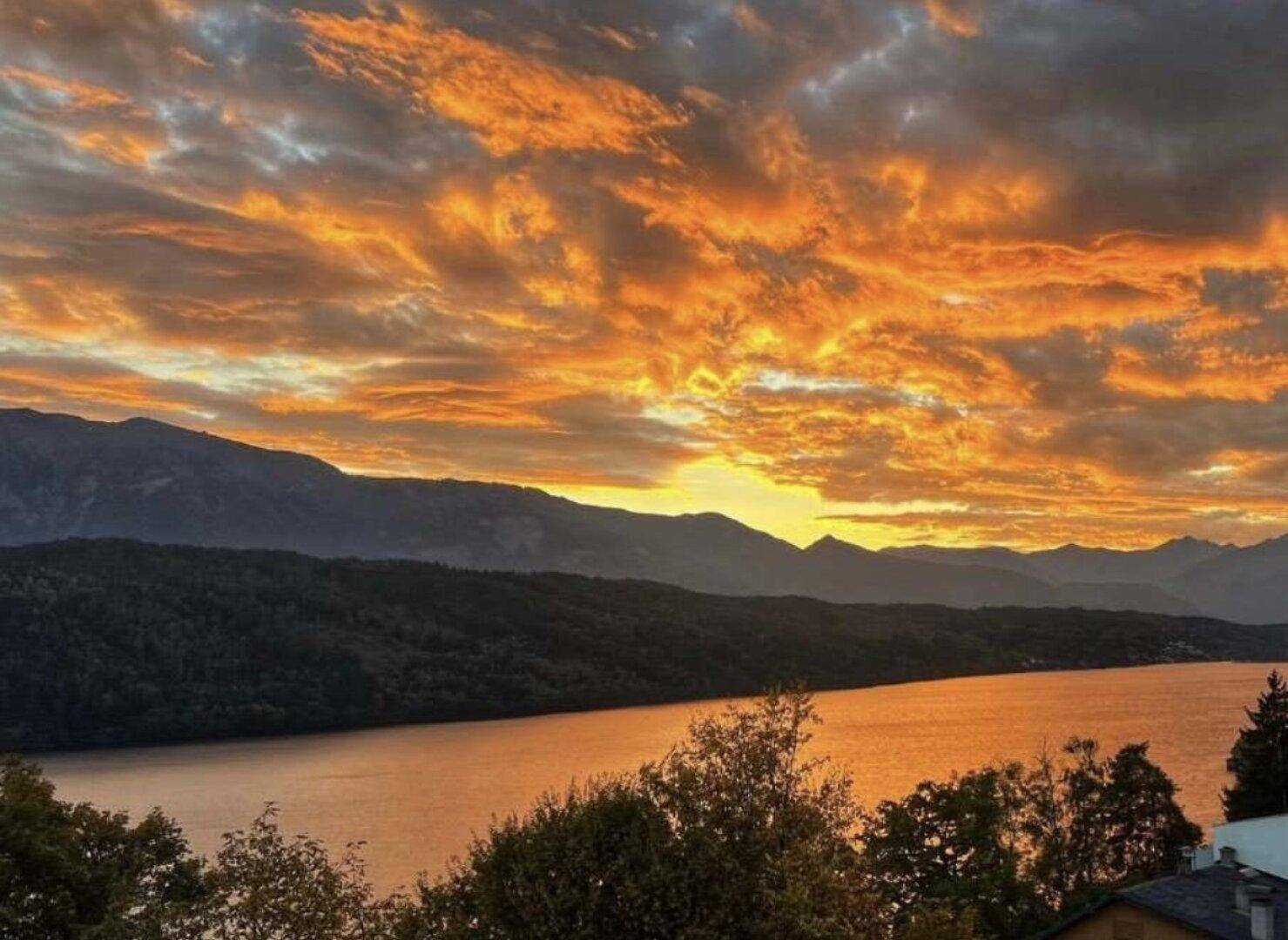Spektakulärer Sonnenuntergang über dem See und den Bergen, der den Himmel in warmen Farben färbt.