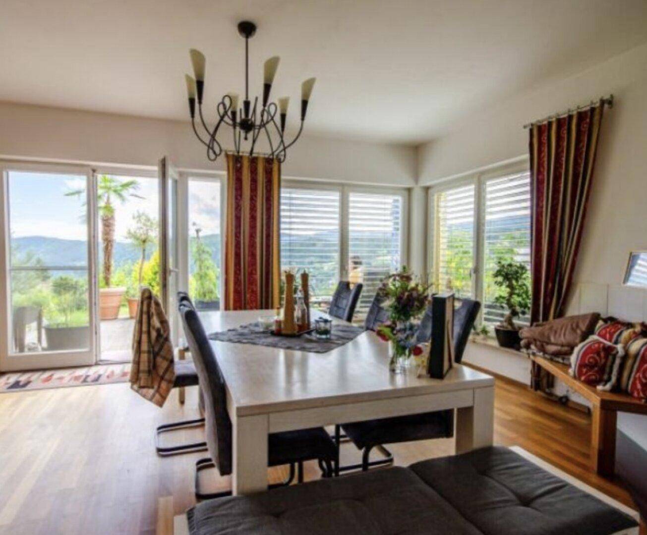 Heller Essbereich mit großem Tisch, Parkettboden und Zugang zu einem Außenbereich mit schöner Aussicht.