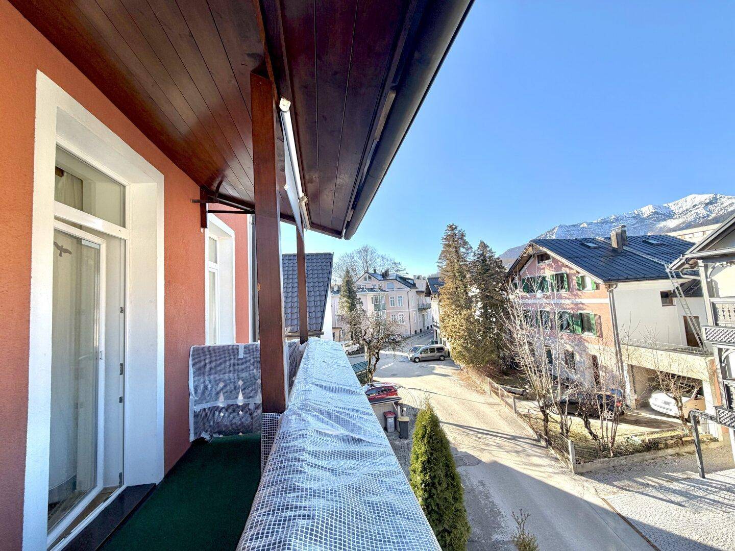 Balkon mit Holzboden und Blick auf die umliegenden Häuser und Berge.