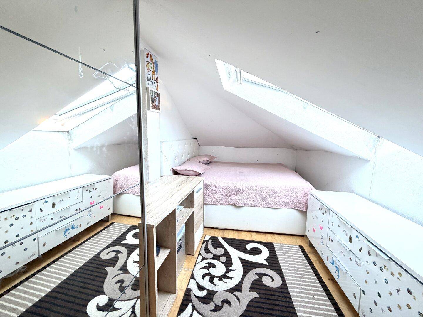 Gemütliches Schlafzimmer im Dachgeschoss mit Dachschrägen, Dachfenstern und Stauraum.