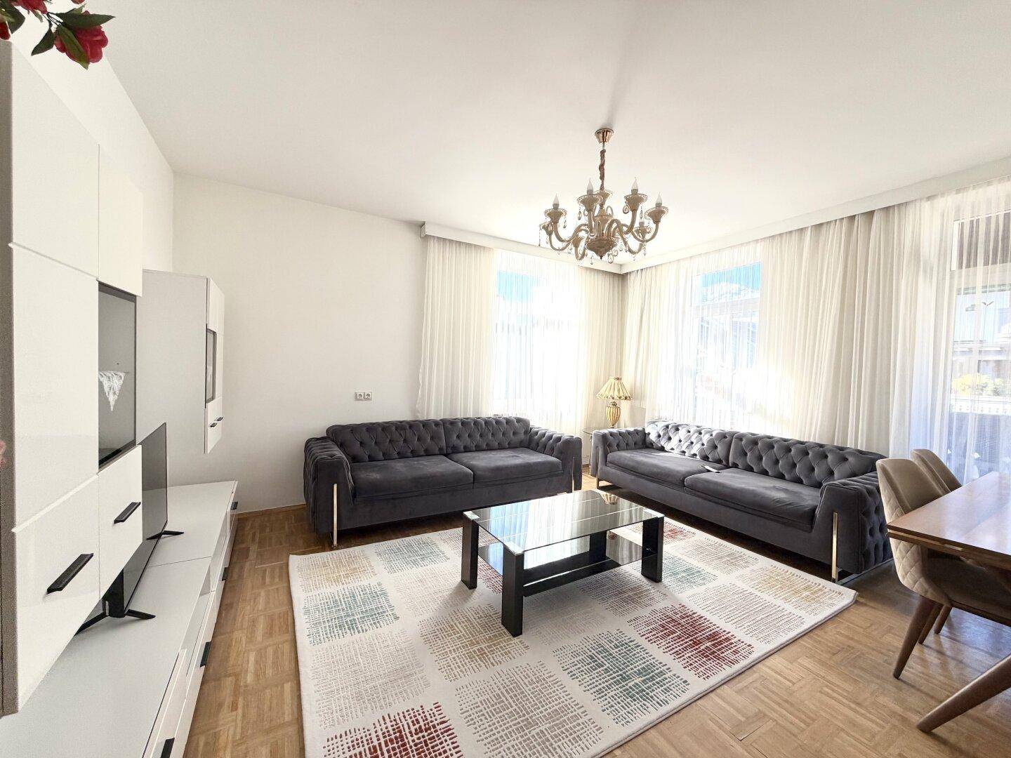 Geräumiges Wohnzimmer mit zwei modernen Sofas, Couchtisch und großem Fenster.