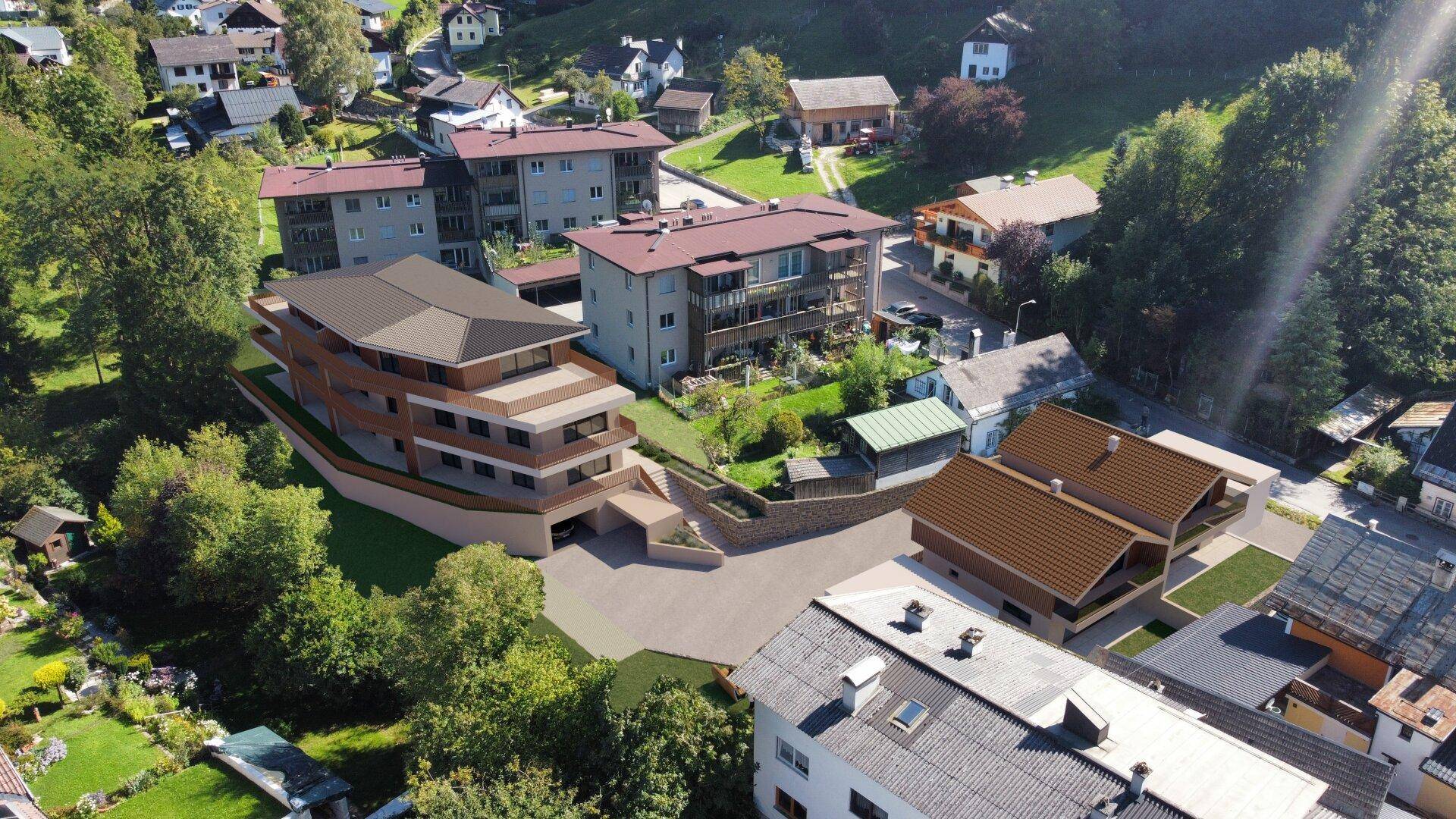 Vogelperspektive einer modernen Wohnanlage in grüner Umgebung mit Bergblick.