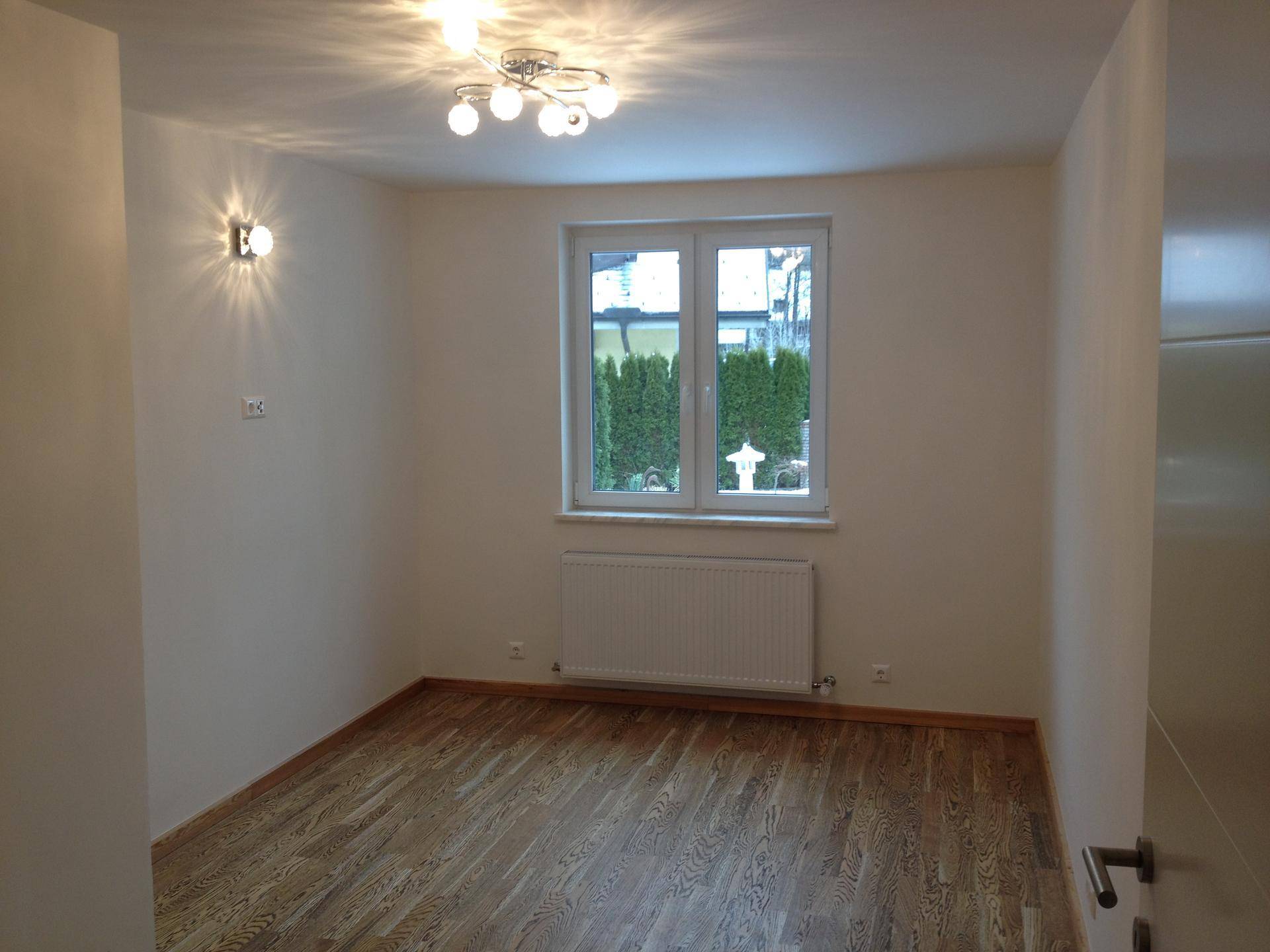 Helles Zimmer mit Holzfußboden, Fenster und Heizkörper, ideal als Schlaf- oder Arbeitszimmer.