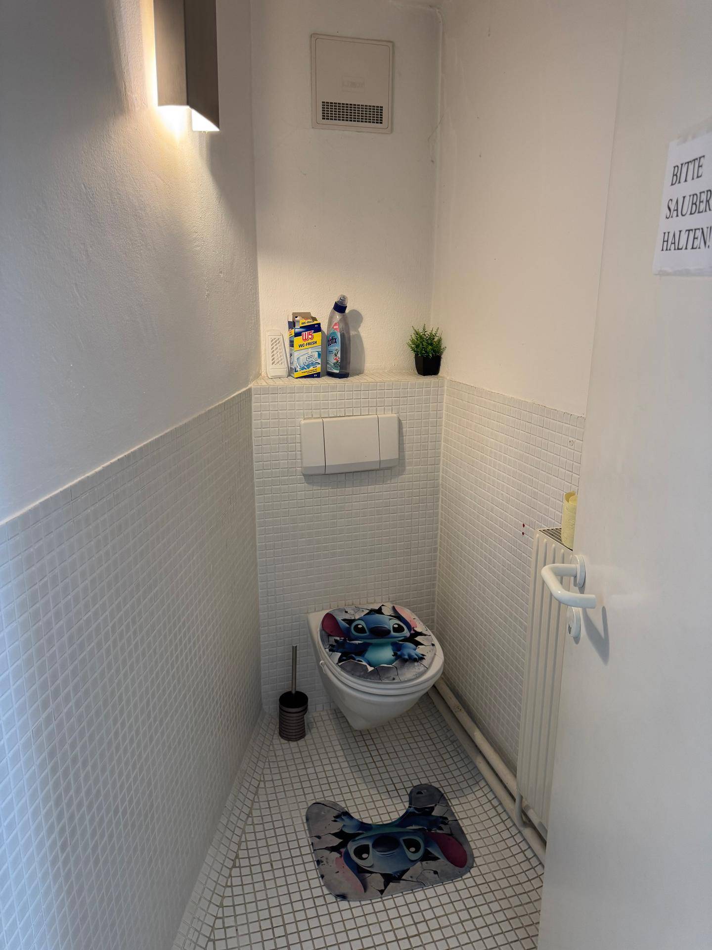 Separate Toilette mit Wand-WC und kleinen weißen Fliesen.