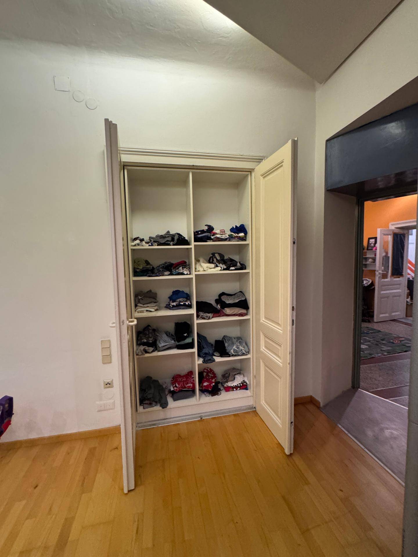 Flur mit eingebautem Kleiderschrank und Holzfußboden, der zu weiteren Räumen führt.