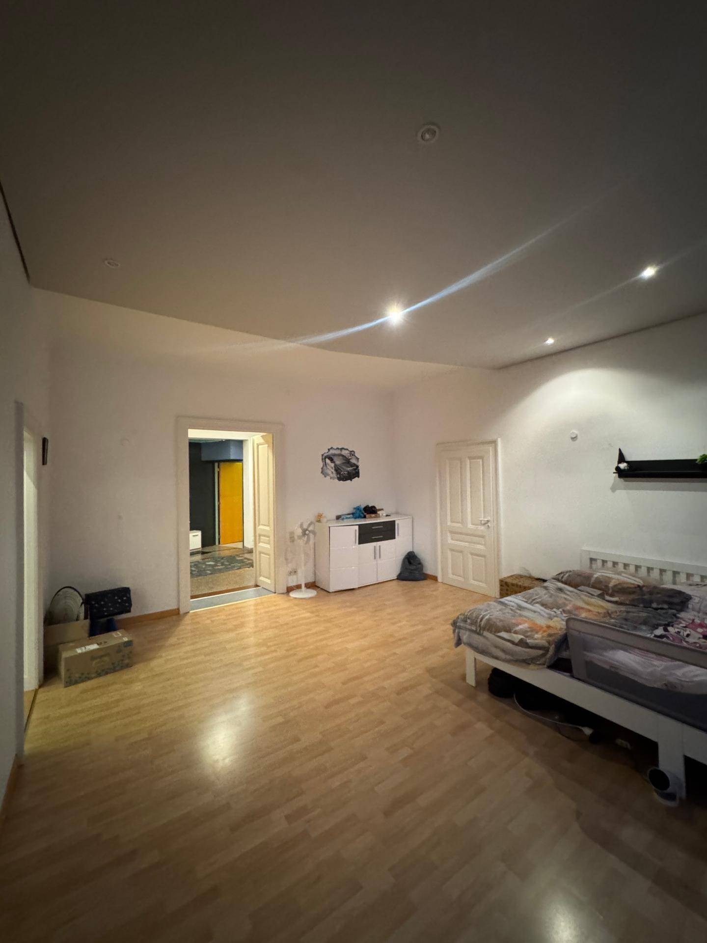 Schlafzimmer mit Parkettboden und Zugang zu einem weiteren Raum.