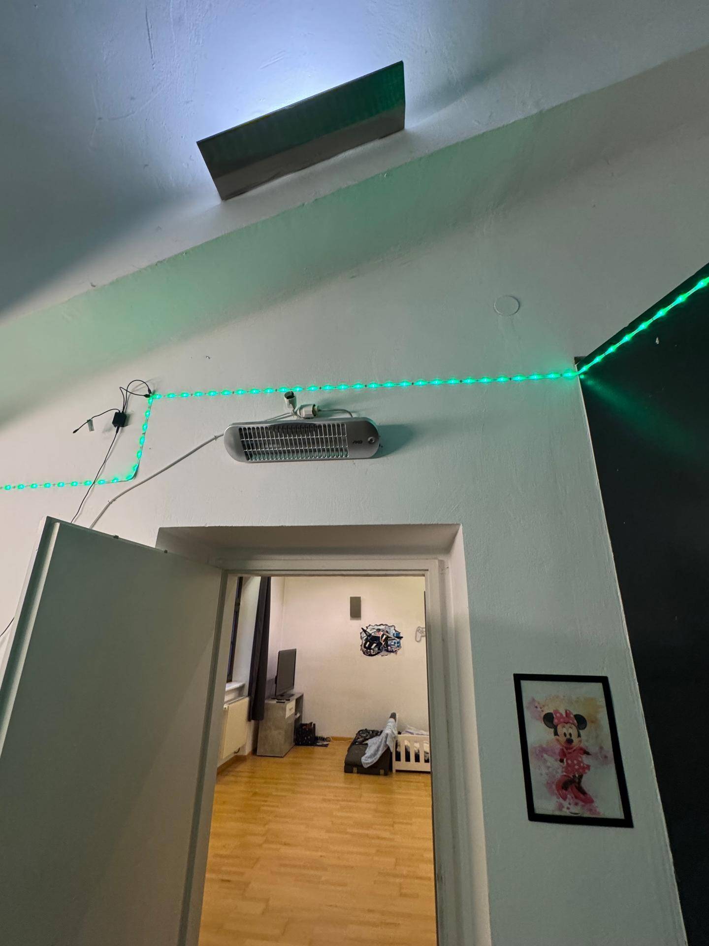 Flur mit schräger Decke, grünen LED-Lichtern und Blick in ein angrenzendes Zimmer.