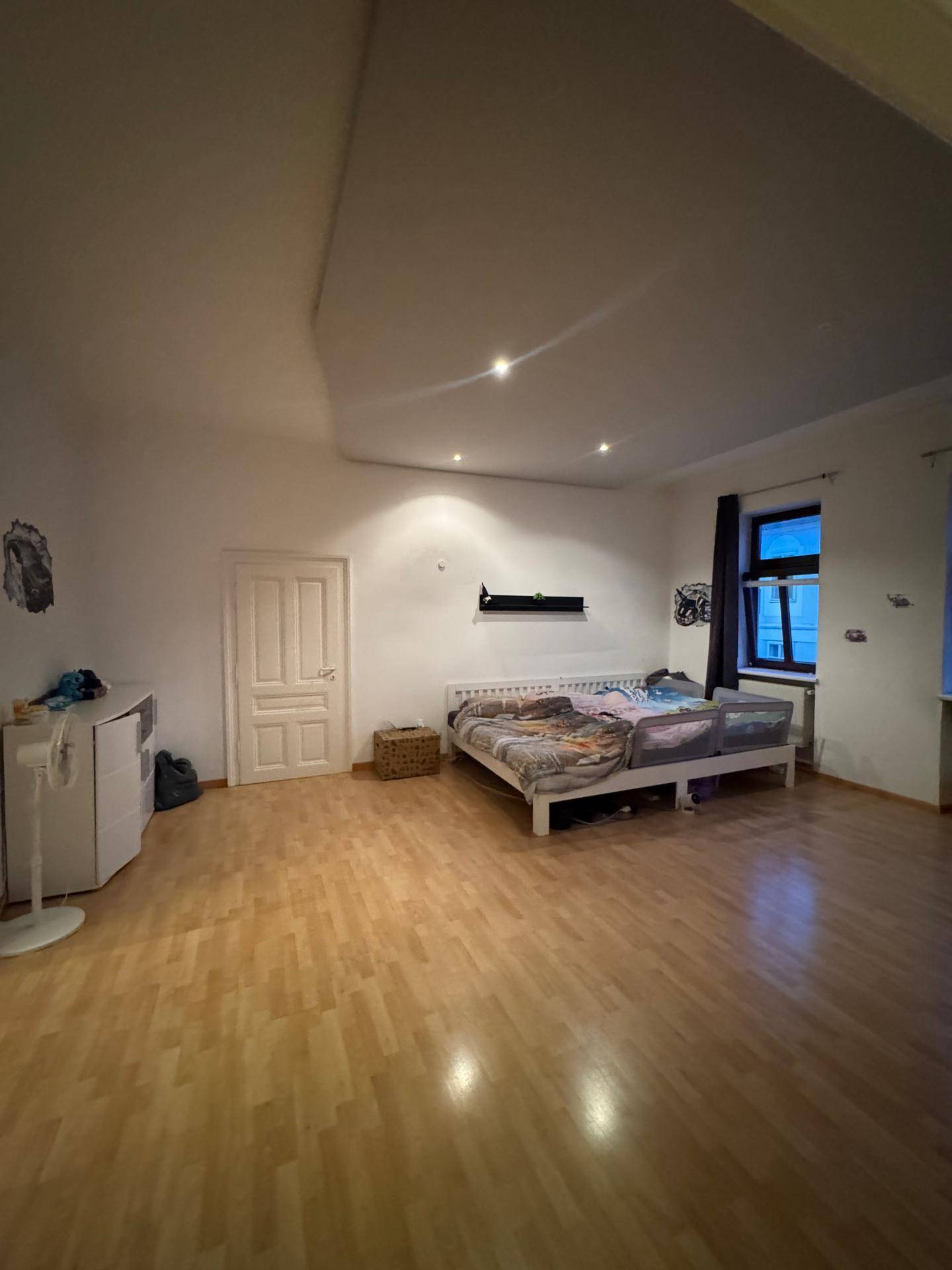 Schlafzimmer mit Parkettboden, Doppelbett und integrierter Deckenbeleuchtung.
