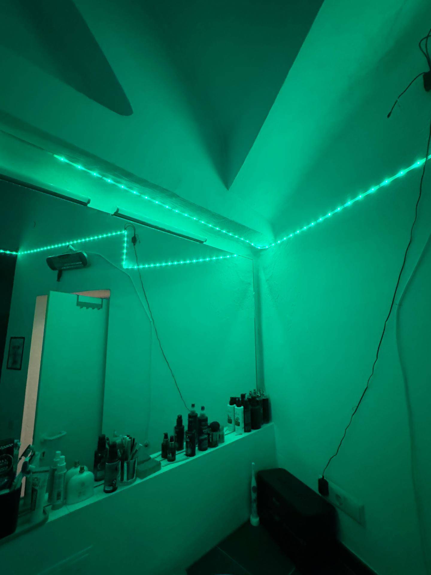 Badezimmer mit grüner LED-Beleuchtung und einem großen Spiegel.