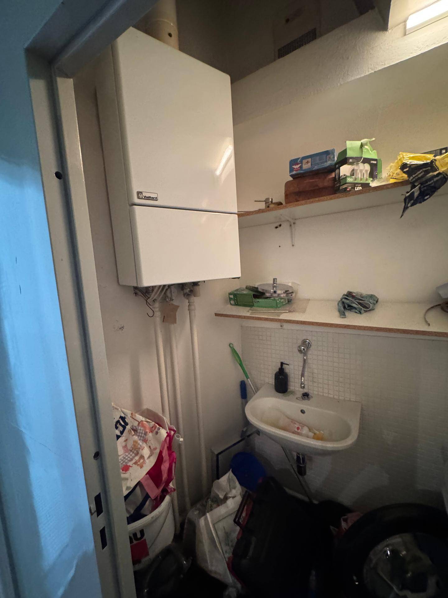 Kleiner Hauswirtschaftsraum mit Heizungsanlage, Waschbecken und Regalen.