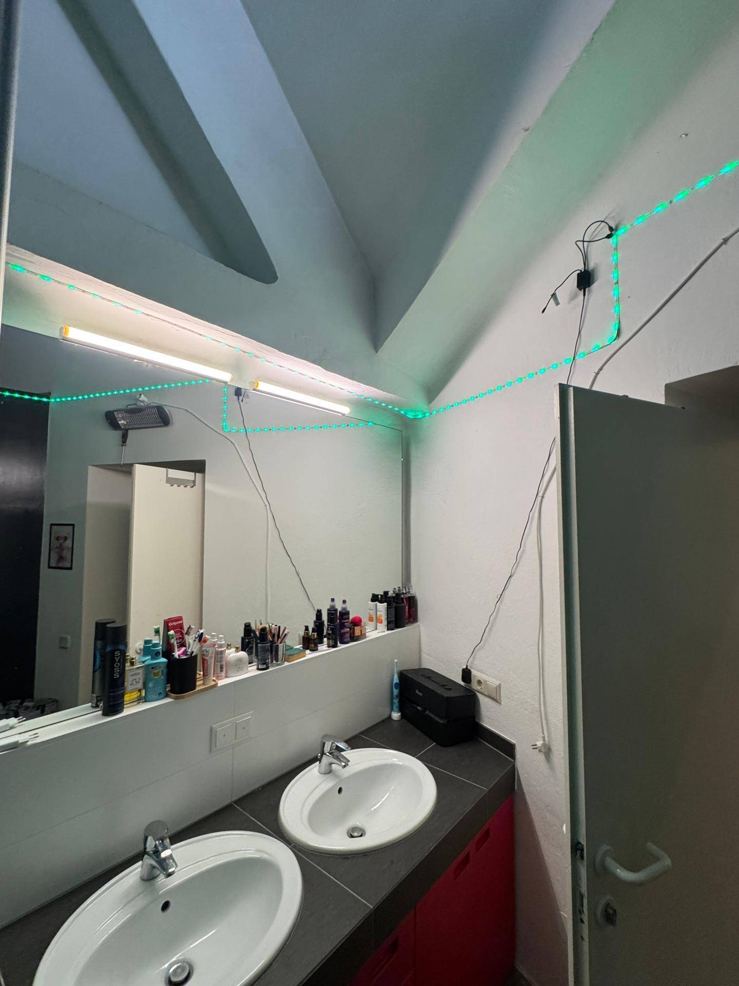 Modernes Badezimmer mit Doppelwaschbecken, großem Spiegel und grüner LED-Beleuchtung.