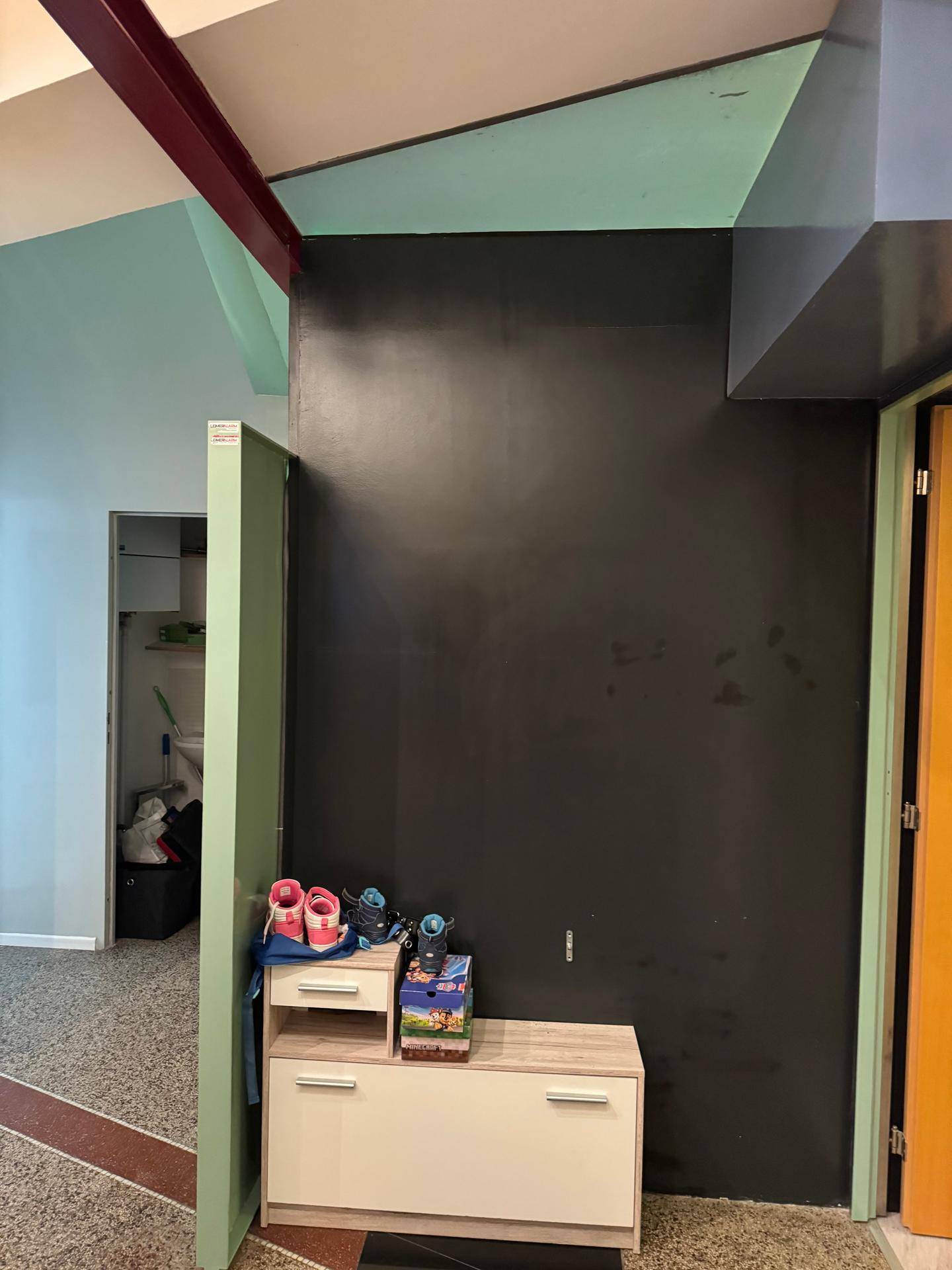 Flur mit dunkler Wand und einem kleinen Schuhschrank, der Stauraum bietet.