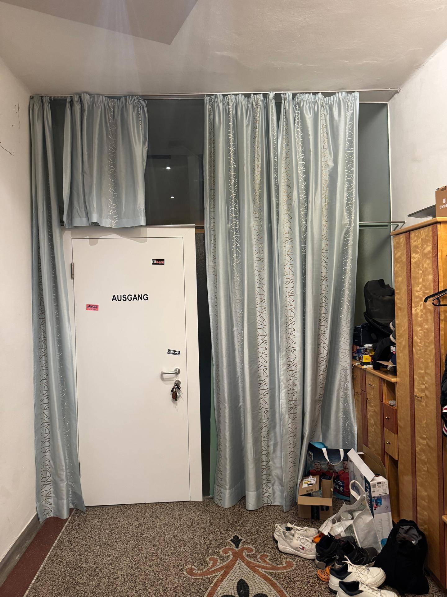 Eingangsbereich mit Vorhängen vor der Tür und einem Schrank, der als Stauraum dient.