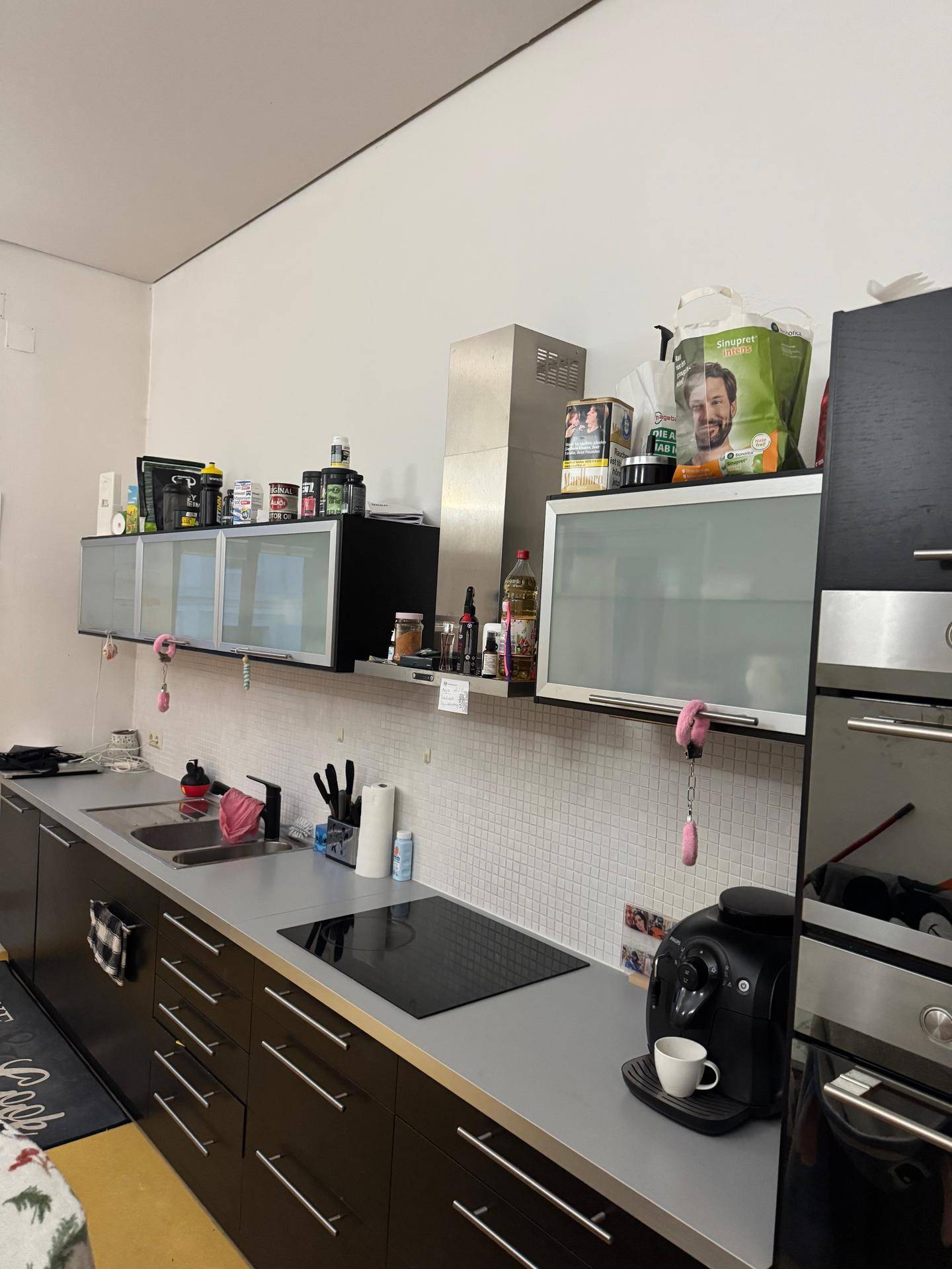 Moderne Küche mit dunklen Unterschränken, Induktionskochfeld und Hängeschränken.