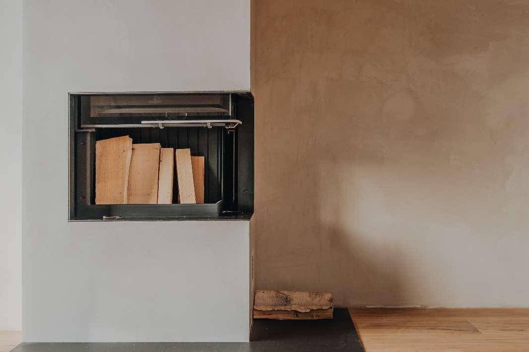Moderner Kamin mit Holzscheiten, bereit für gemütliche Abende im Wohnzimmer.