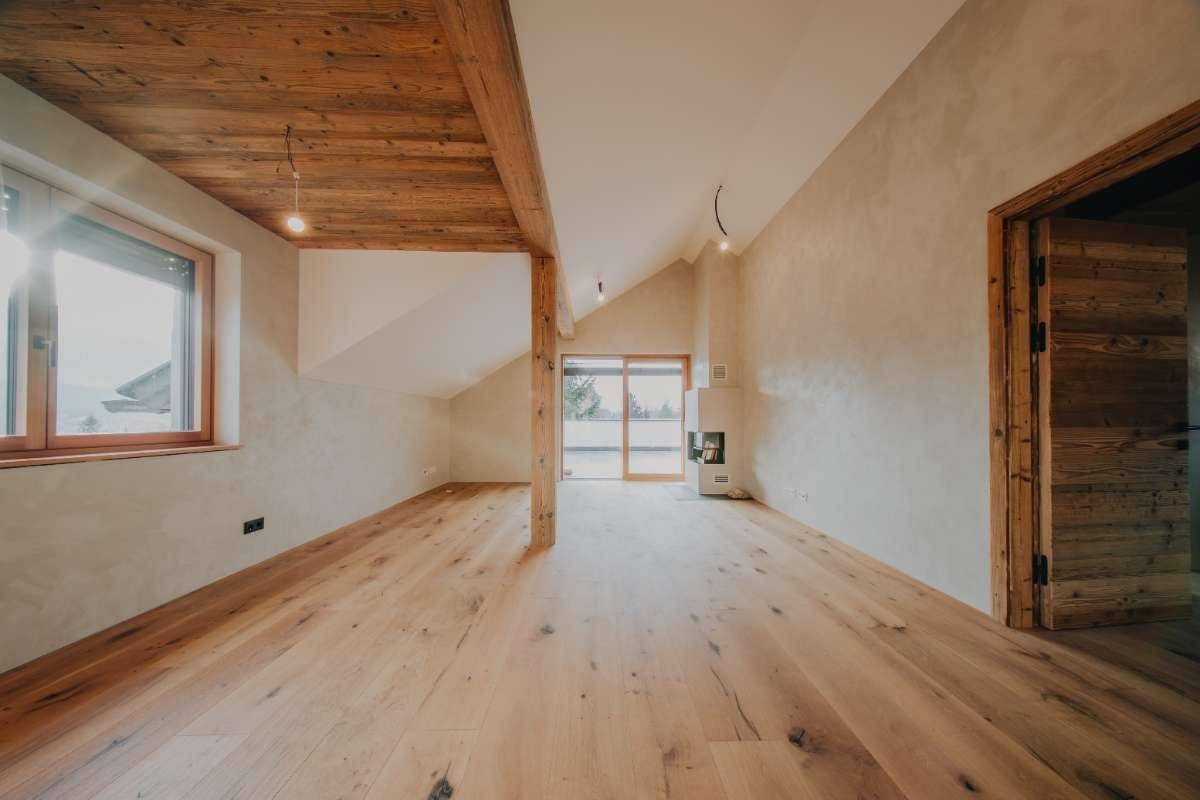 Heller Wohnraum mit Holzboden, Kamin und Zugang zur Dachterrasse mit Bergblick.