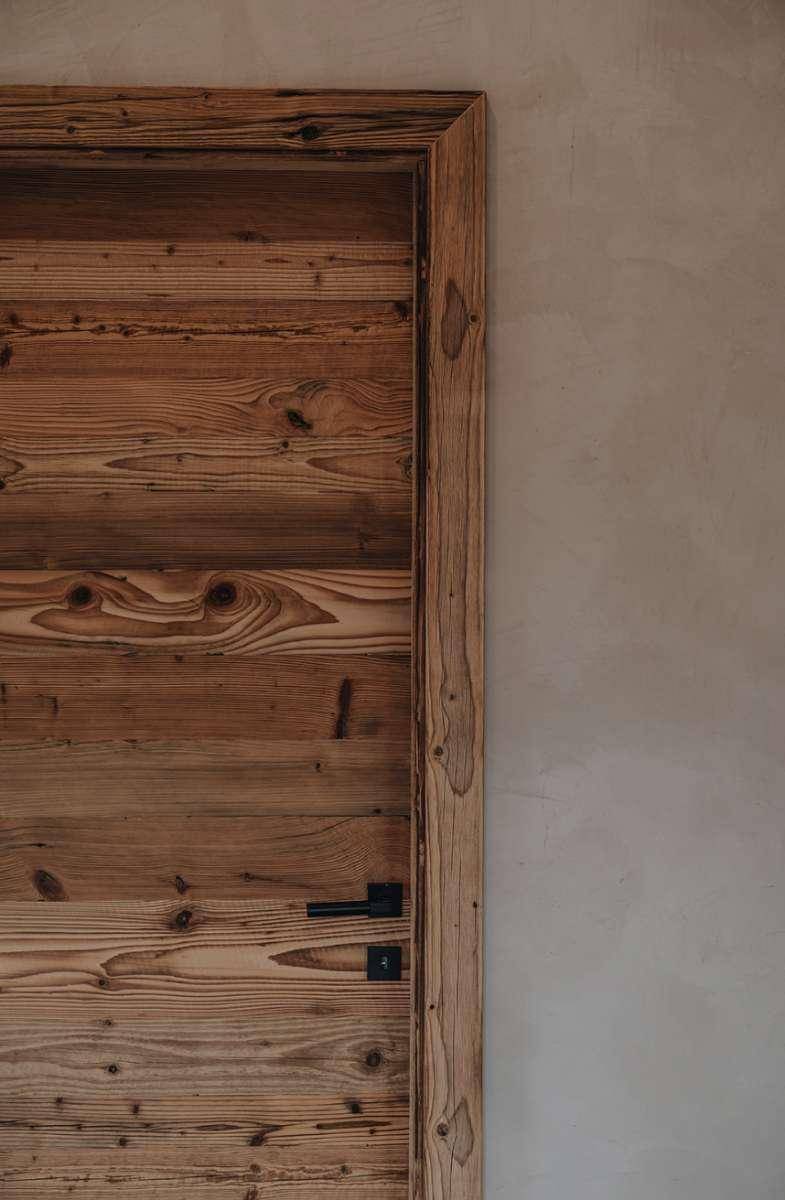 Rustikale Holztür mit moderner schwarzer Klinke, die den natürlichen Stil unterstreicht.
