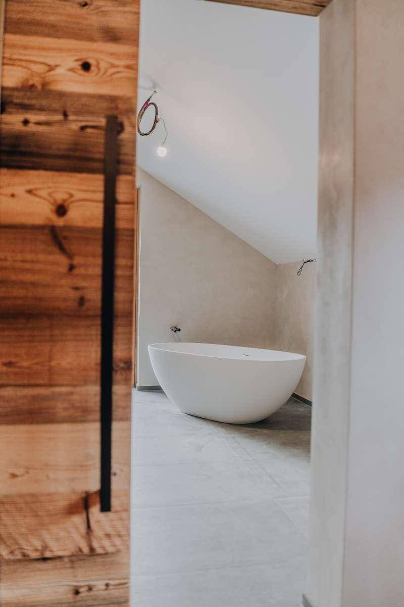 Elegante freistehende Badewanne in einem hellen Badezimmer mit schrägen Wänden.