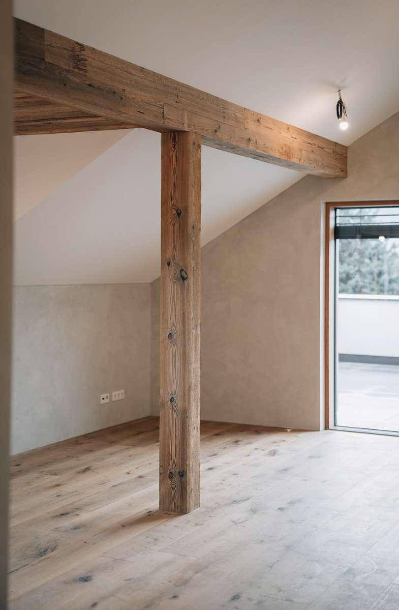 Innenraum mit sichtbarem Holzbalken und Zugang zu einer Außenterrasse.