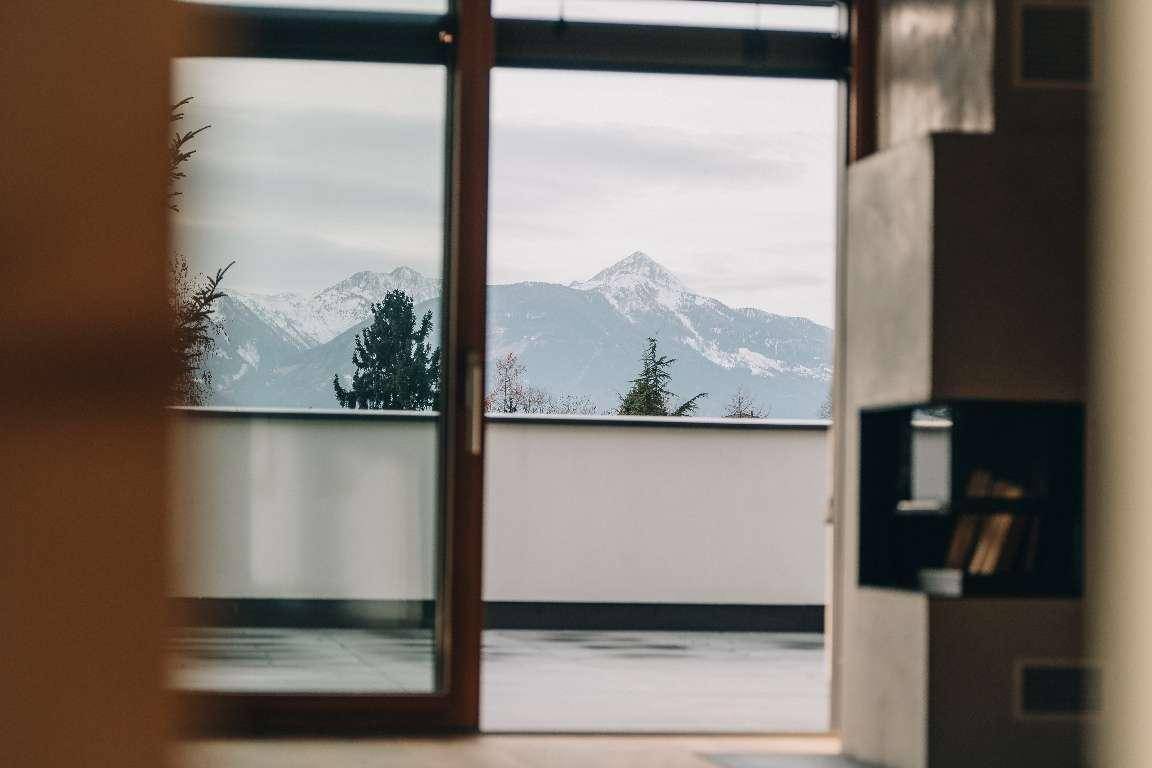 Atemberaubender Blick auf die schneebedeckten Berge durch die Terrassentür.