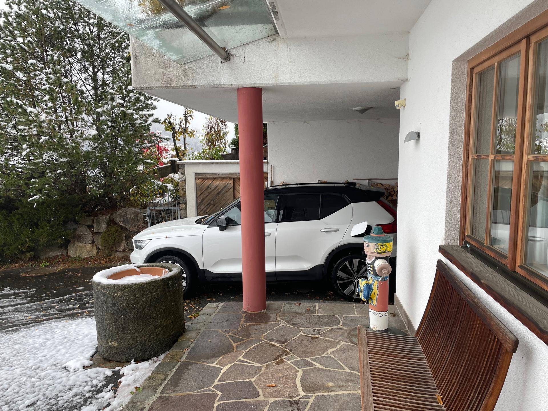 Überdachter Stellplatz für ein Fahrzeug mit Steinboden und leichter Schneedecke.