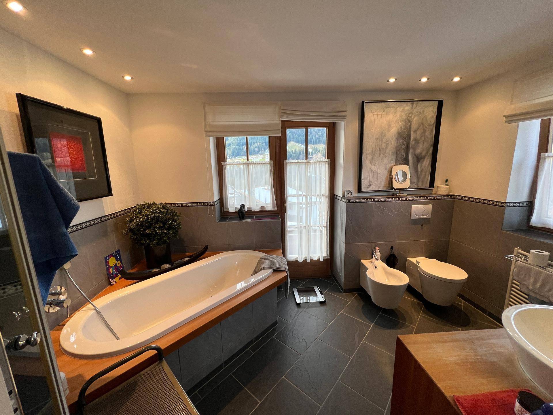 Modernes Badezimmer mit Badewanne, Bidet und Fenster für natürliches Licht.
