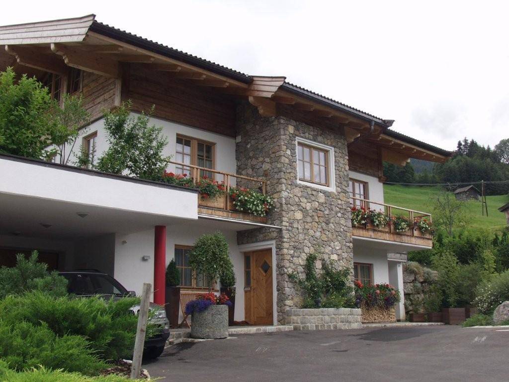 Attraktives Haus mit Steinfassade, Holzelementen und gepflegter Auffahrt in ländlicher Umgebung.