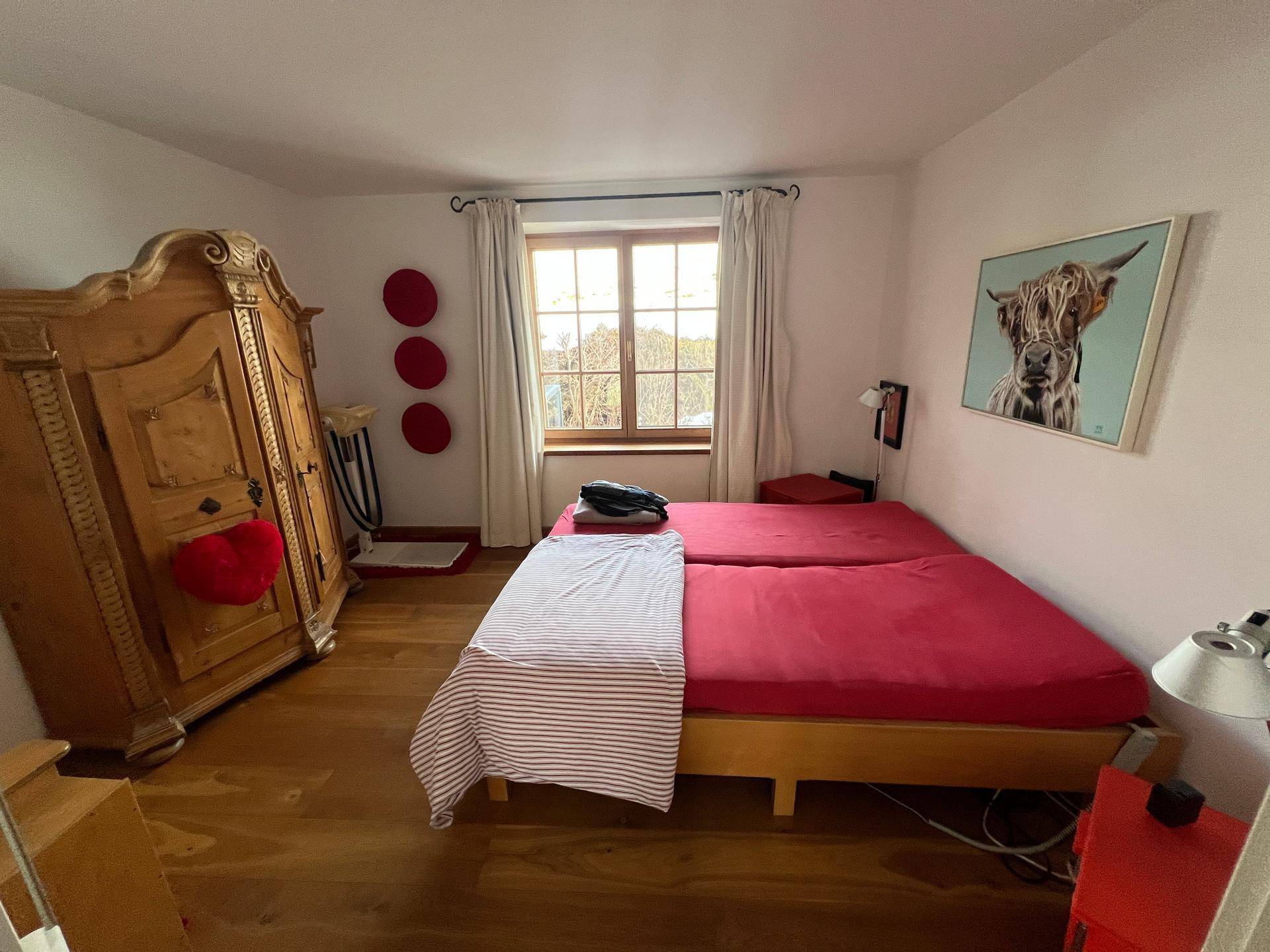 Schlafzimmer mit Holzboden, traditionellem Kleiderschrank und Fenster mit Ausblick.