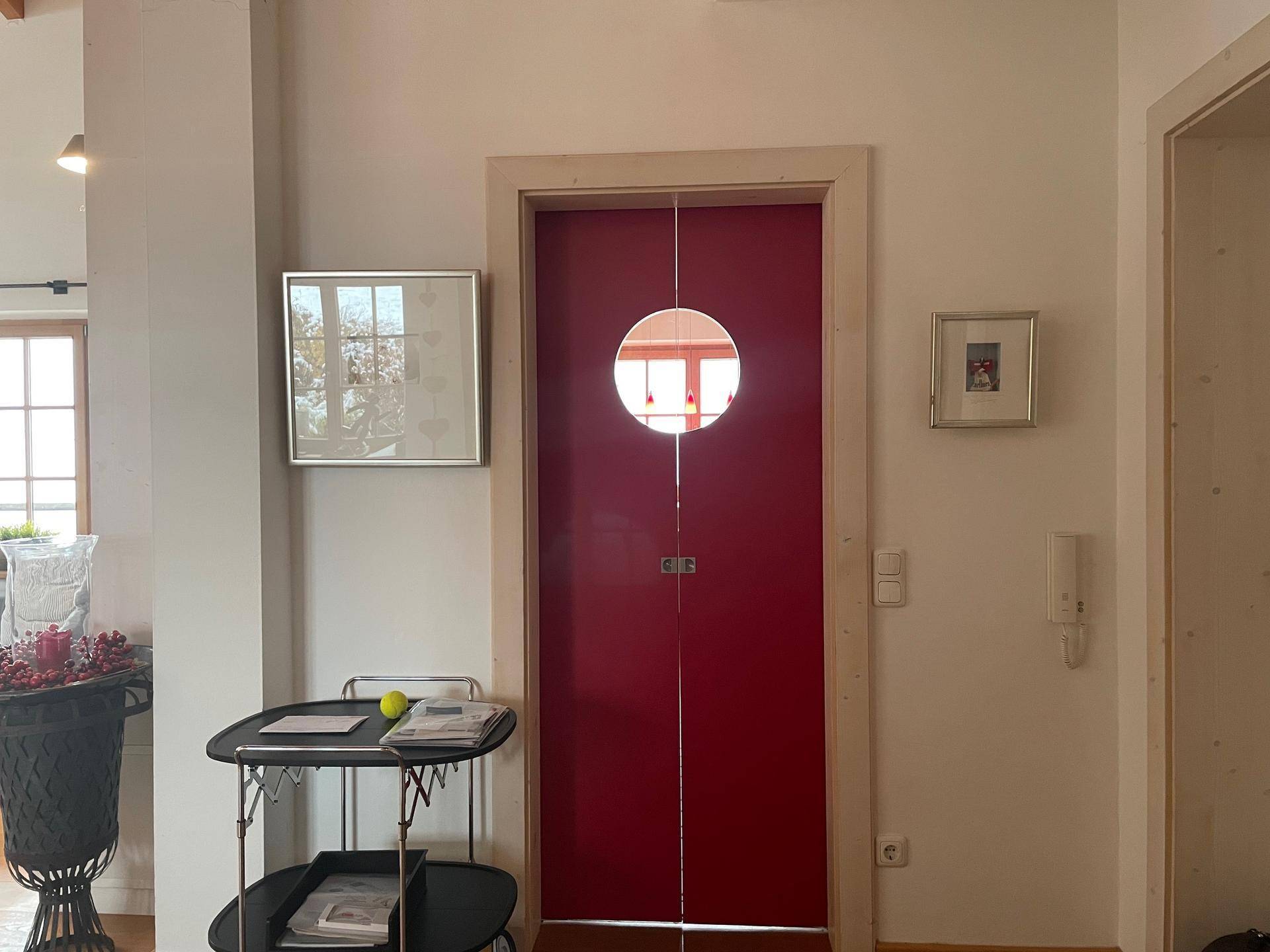 Heller Flur mit einer auffälligen roten Tür und Blick in den Wohnbereich.
