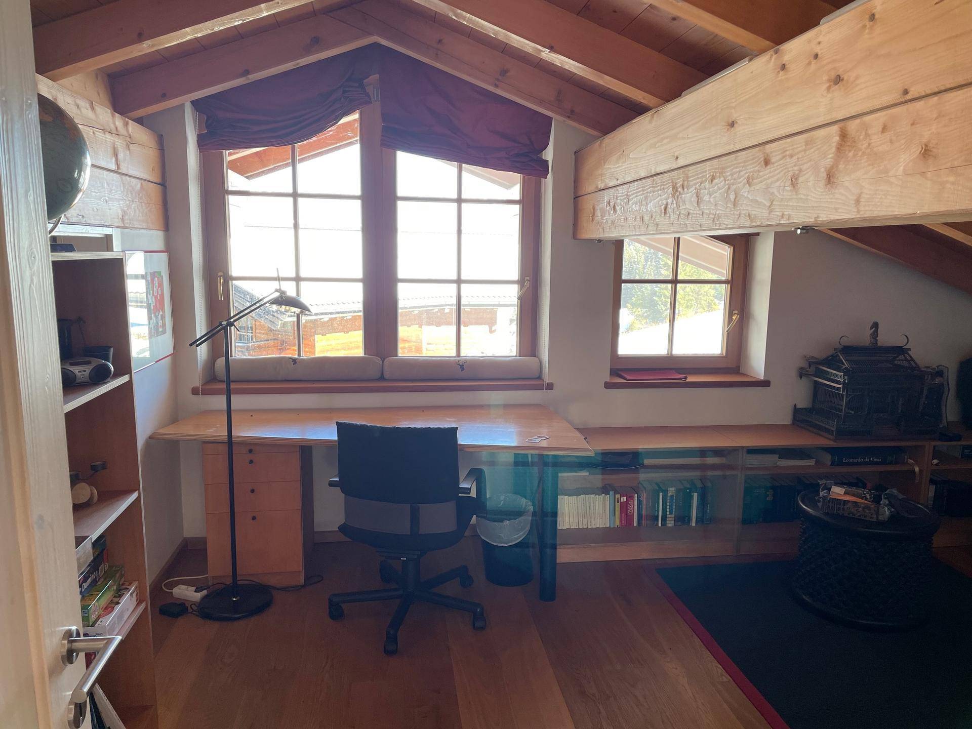 Helles Dachgeschoss-Arbeitszimmer mit Holzbalken, Schreibtisch und Dachfenstern.