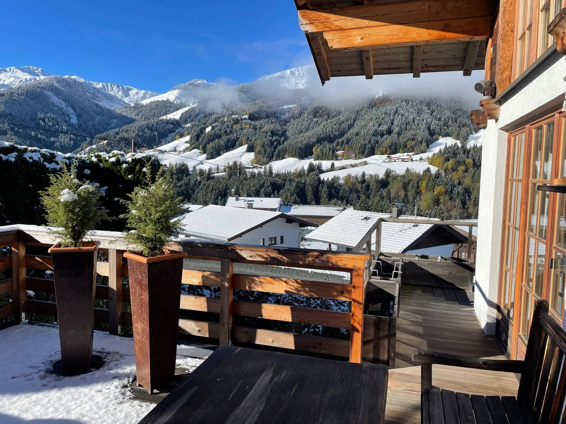 Balkon mit Holzboden und Geländer, bietet einen weiten Blick auf die verschneite Berglandschaft.
