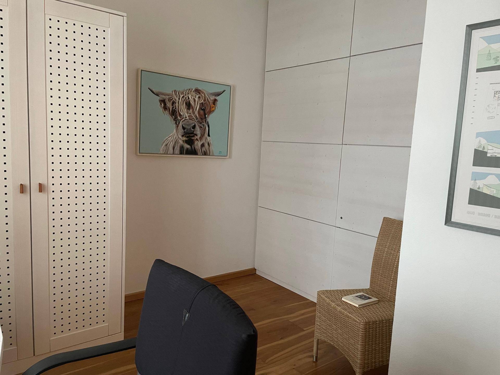 Arbeitsbereich mit Schreibtisch, Schrank und moderner Wandgestaltung.